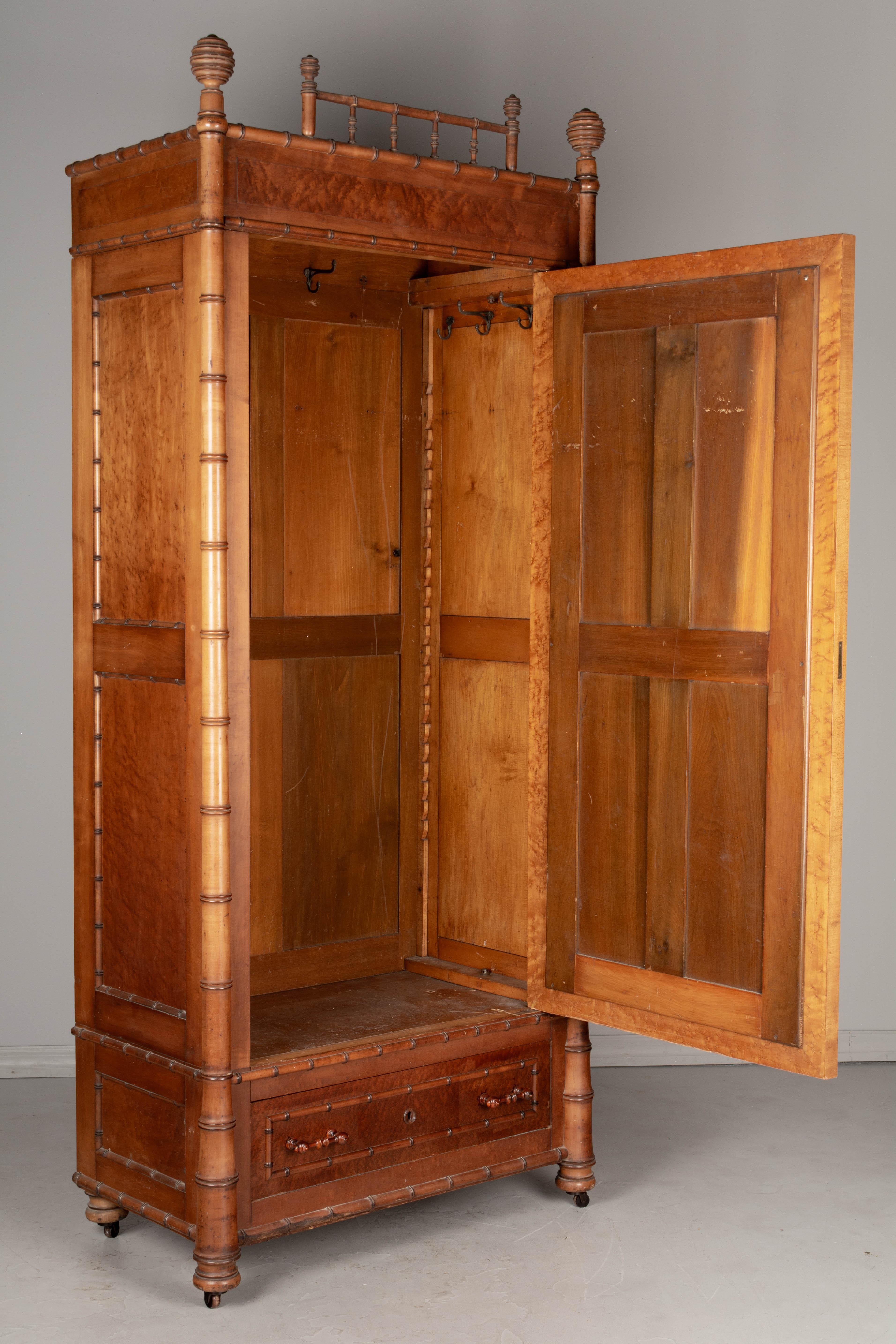 A 19th century American Victorian Aesthetic Movement faux bamboo armoire and bedside table by R.J. Horner made of solid cherry and amber stained birds eye maple. The armoire, or wardrobe, has a beveled mirror door with working lock and key (new