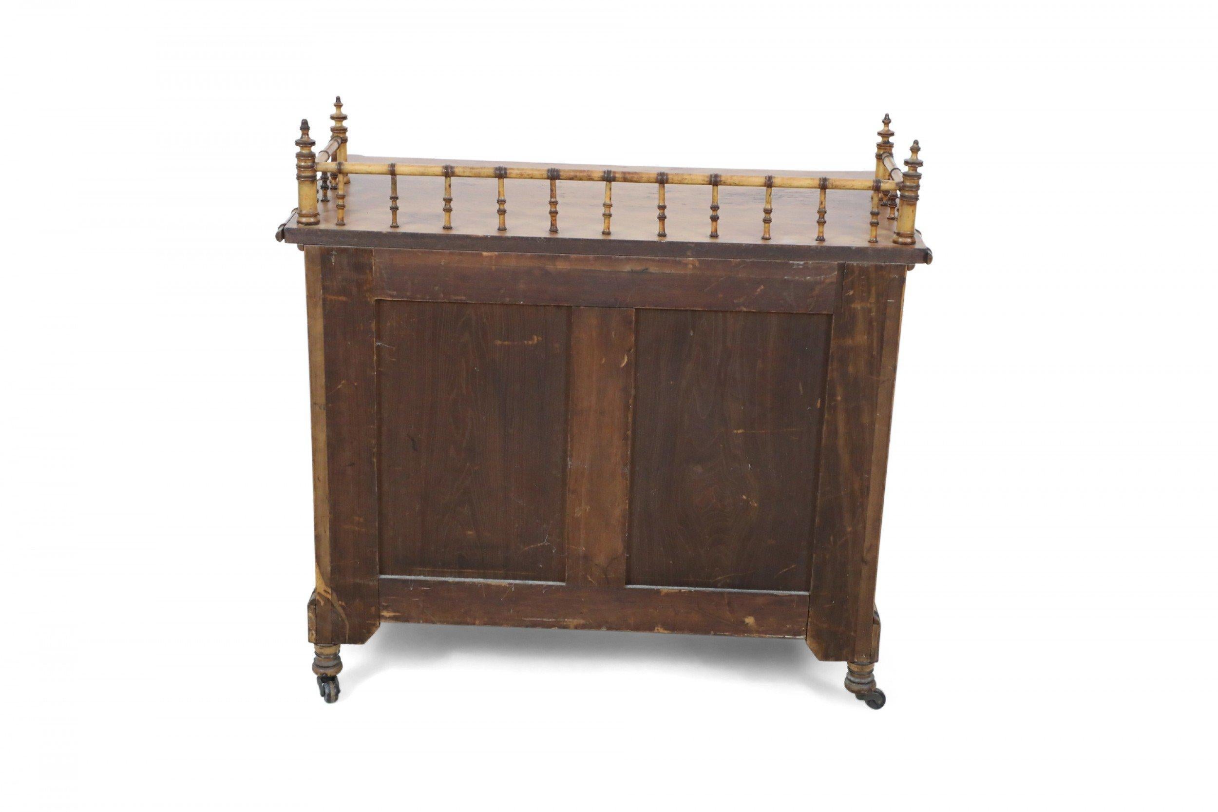 American Victorian Aesthetic Movement amber stained birdseye maple faux bamboo commode with a partial gallery top, paneled sides, and turned wooden handles on two cabinet doors beneath a single drawer, resting on brass casters. (att: RJ HORNER).
  