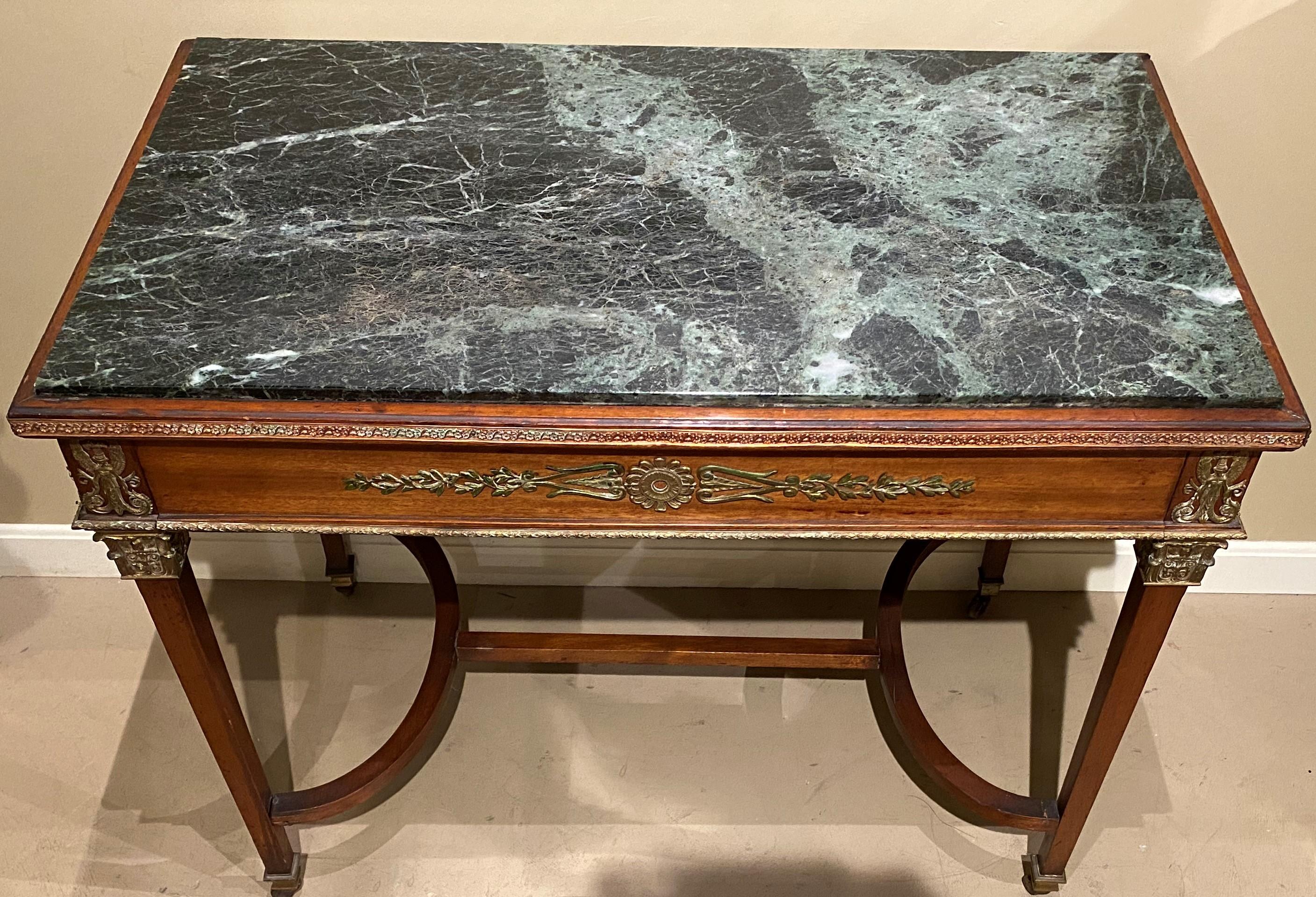 A beautiful French mahogany one-drawer rectangular writing table with green variegated marble top, with well articulated cast doré foliate ormolu and edge banding on the frieze on all four sides, as well as figural ormolu on each corner, supported