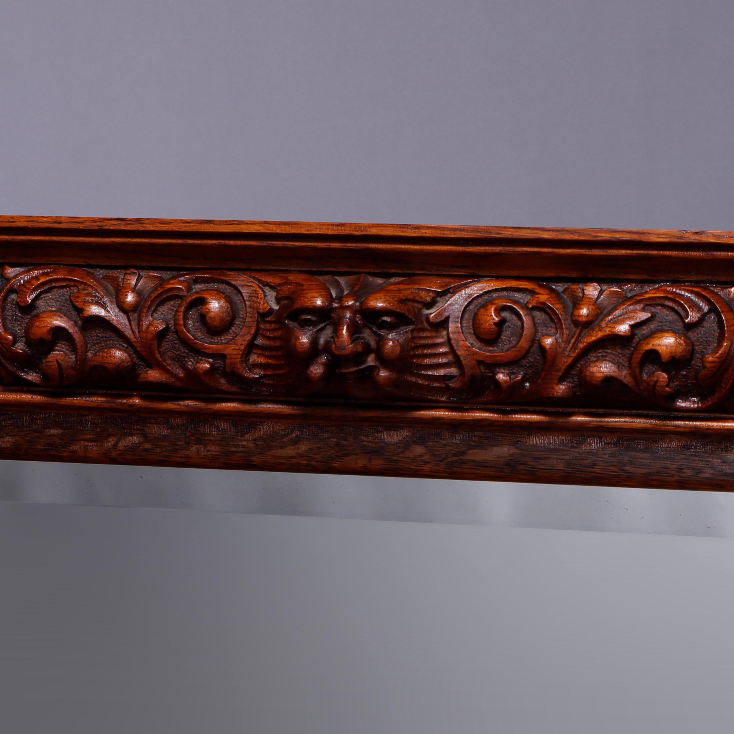 An antique sideboard in the manner of RJ Horner offers quarter sawn oak construction with carved frieze having central grotesque mask flanked by foliate elements over oval mirror surmounting lower case having convex double drawers over long drawer