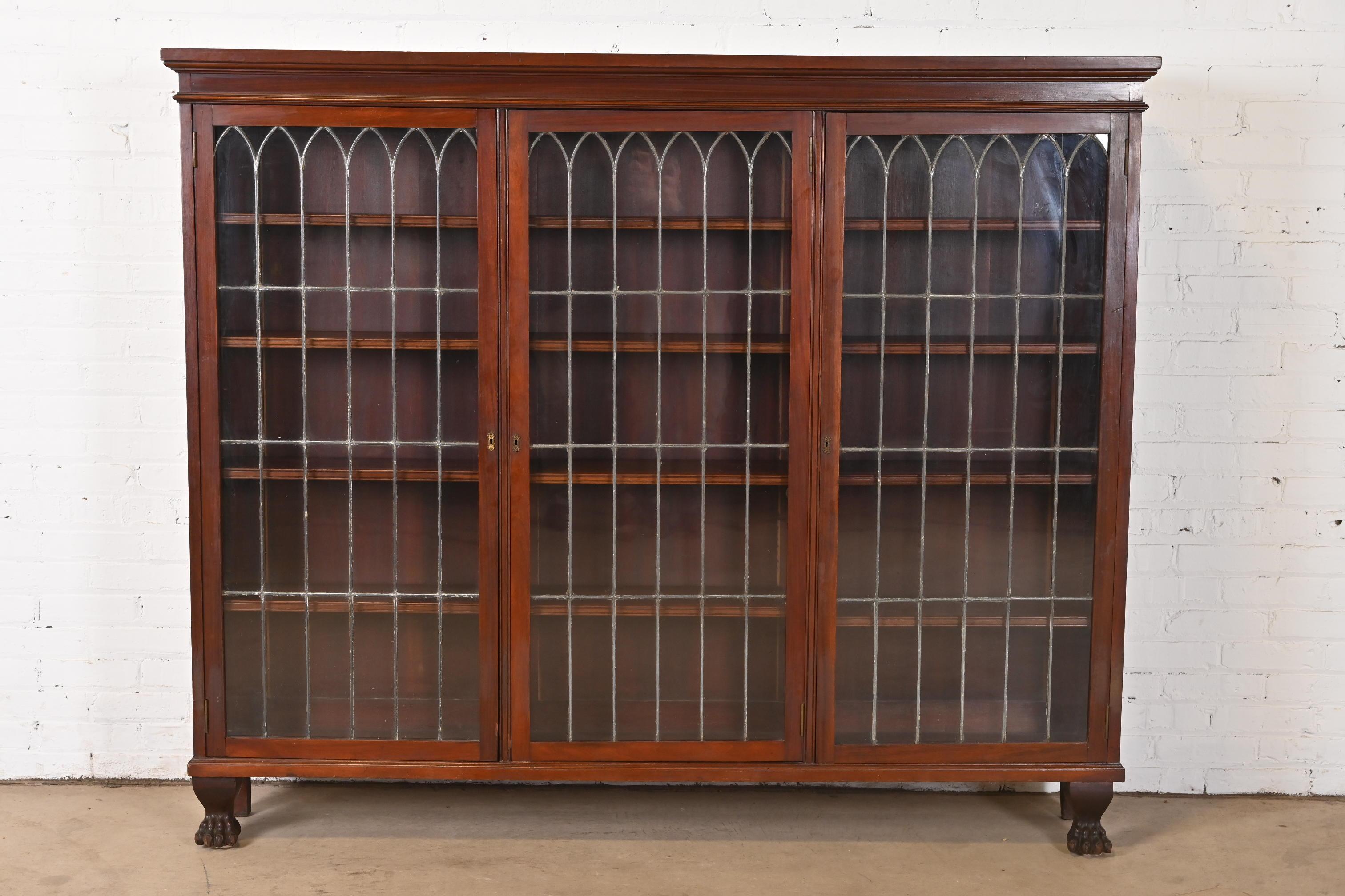 An exceptional antique Late Victorian or Arts & Crafts triple bookcase

In the manner of R.J. Horner

USA, Late 19th Century

Carved mahogany, with original leaded glass doors and brass hardware, and paw feet.

Measures: 71.5