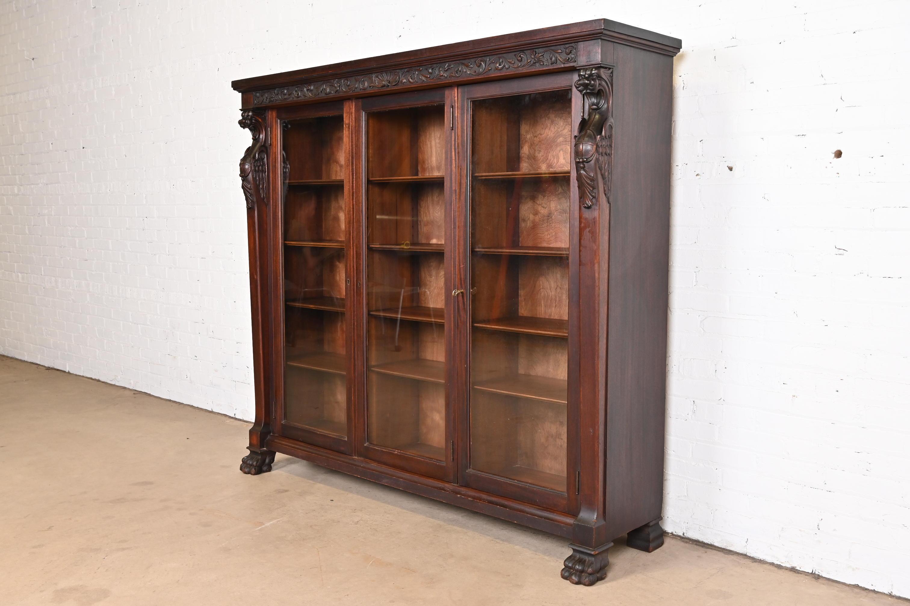 A beautiful antique Victorian or Renaissance Revival glass front triple bookcase with carved griffins and paw feet

Attributed to R.J. Horner & Co.

USA, Circa 1890s

Ornate carved mahogany, with glass front doors. Cabinets lock, and key is