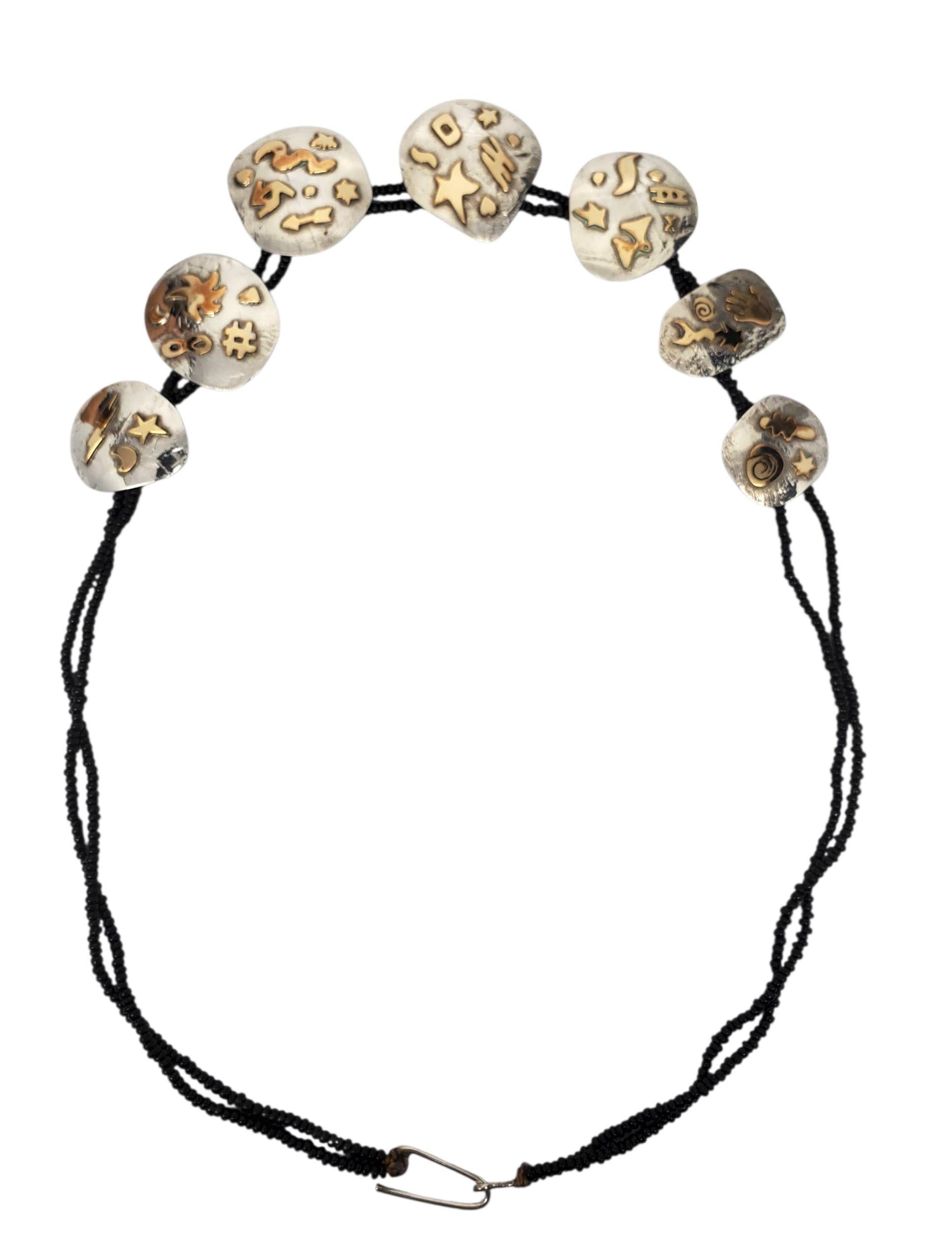 Collana con motivi in argento 925 e placcata in oro - RLA

Questa collana in argento sterling RLA fatta a mano presenta sette placche ovali martellate con motivi dorati in rilievo, tra cui stelle, animali, spirali e simboli celesti.
Doppio filo di