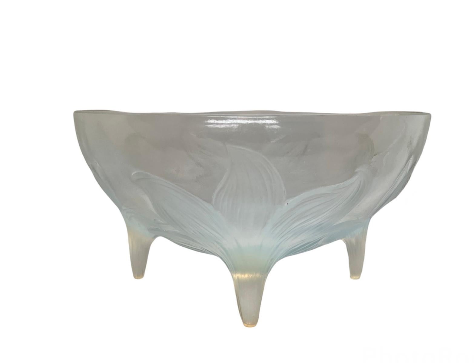 This is a R.Lalique opalescent glass footed bowl adorned with a relief of four large lilies. The R. Lalique hallmark is incised at the bottom.