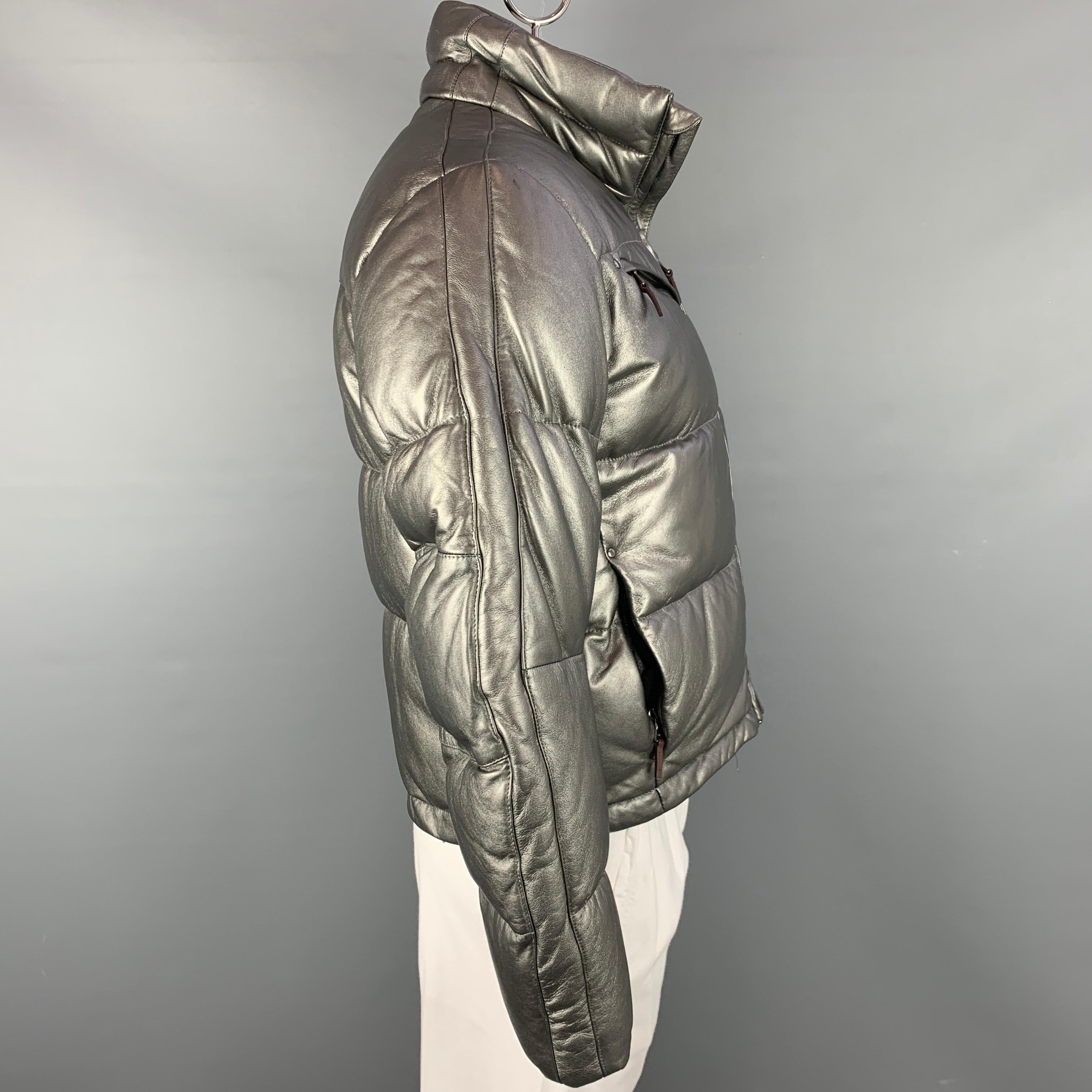 RLX by RALPH LAUREN jacket comes in a silver metallic quilted leather featuring a high collar, slit pockets, and a zip up closure.

New With Tags.
Marked: L

Measurements:

Shoulder: 19 in.
Chest: 46 in.
Sleeve: 26 in.
Length: 25 in.