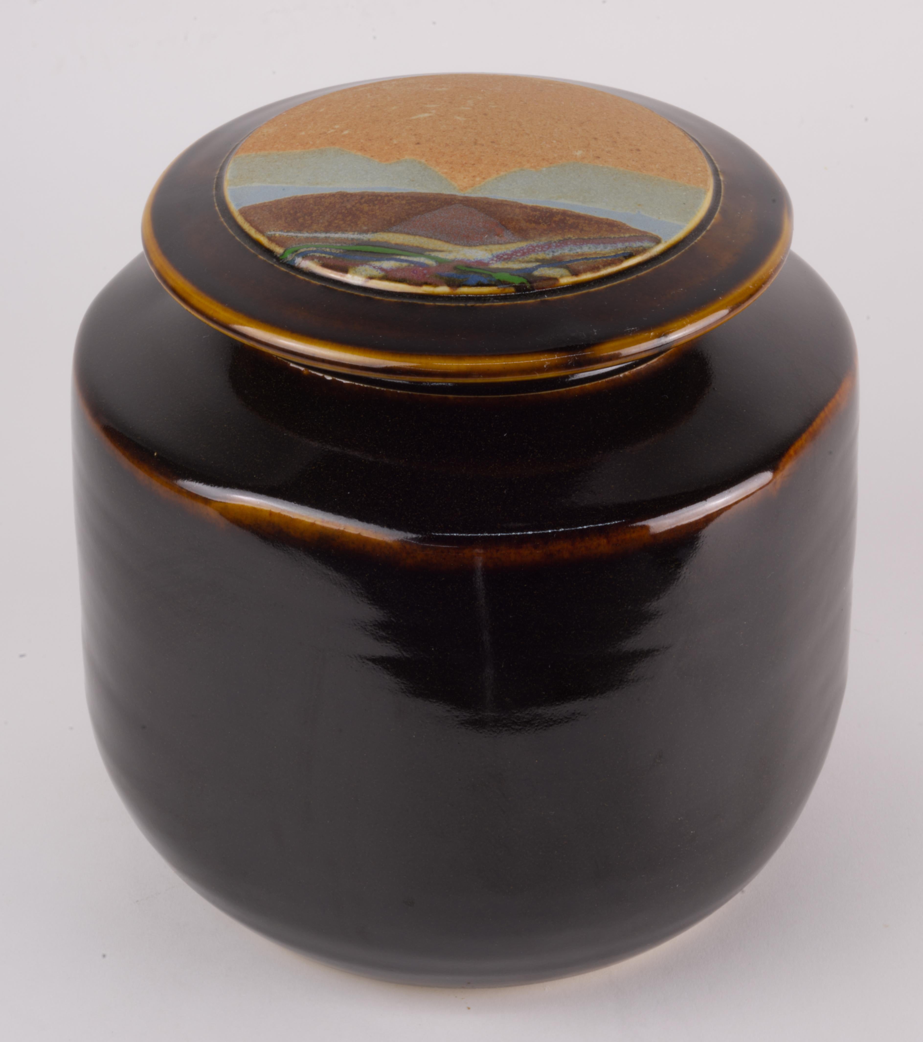  Covered vessel or jar was handmade in white clay by Rob Wiedmaier of River Hills Pottery as a part of a series done in 1980s. The lid of the vessel is decorated with abstract landscape design done in complex mix of multicolored, textured matte and