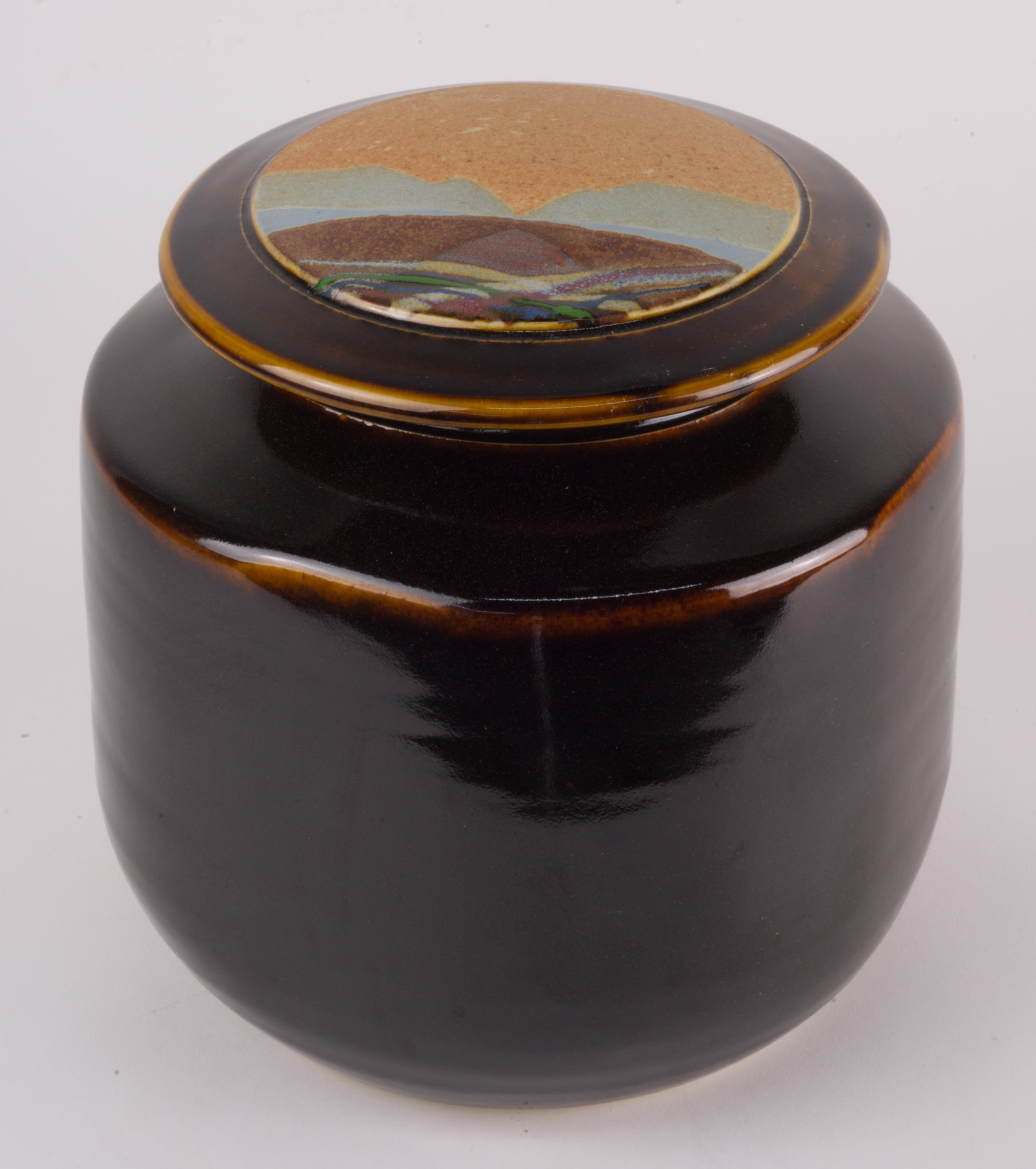  La vasija o jarra cubierta fue hecha a mano en arcilla blanca por Rob Wiedmaier, de River Hills Pottery, como parte de una serie realizada en la década de 1980. La tapa del recipiente está decorada con un diseño paisajístico abstracto realizado en