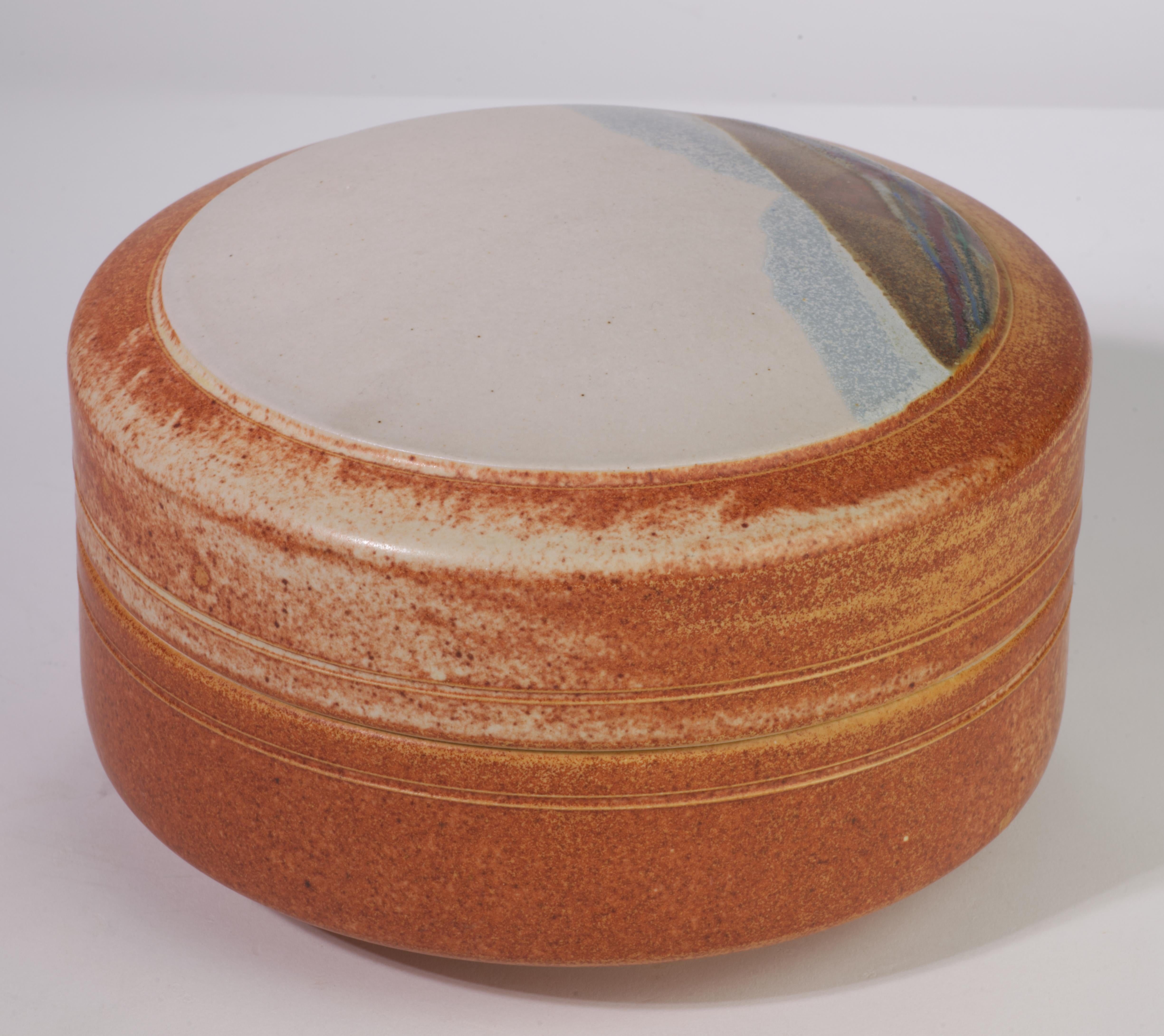  Il vaso coperto è stato realizzato a mano in argilla bianca da Rob Wiedmaier di River Hills Pottery, come parte di una serie realizzata negli anni '80. Il coperchio del vaso è decorato con il disegno di un paesaggio astratto realizzato con un