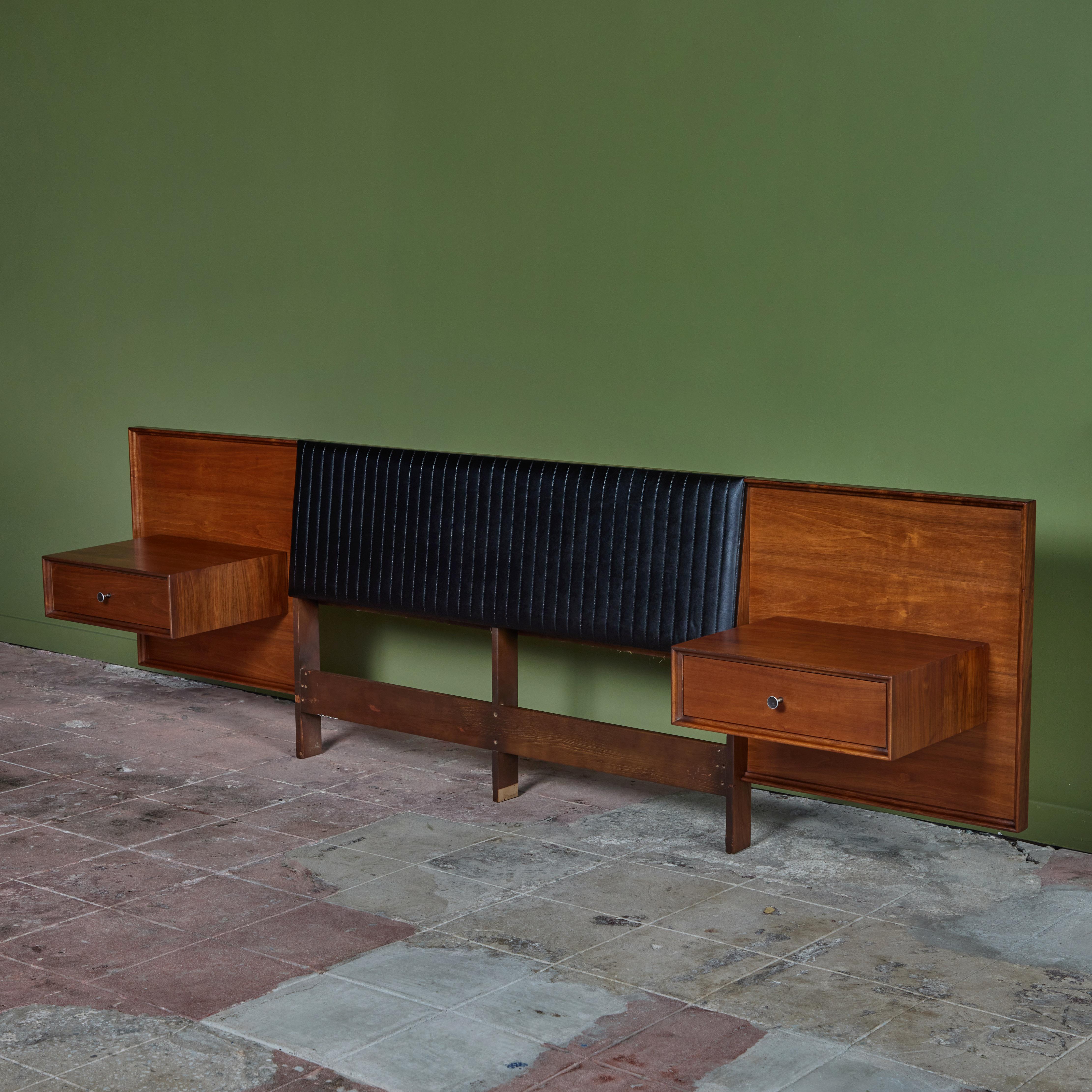 Full size headboard by Robert Baron for Glenn of California c.1960s, USA. The walnut headboard features a vertical stitched Naugahyde headrest with attached nightstands. Each nightstand has one drawer with black enameled pulls.

Dimensions
106.75