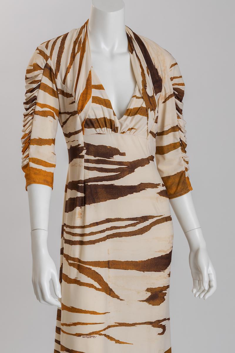 Roberto Cavalli tiger print ivory jersey cocktail dress with 3/4 length sleeves.
This fun dress is form fitted, gathered at the bust with beautiful ruched sleeve detail.
Fabric is soft, luxurious and comfortable. Roberto Cavalli signature is woven