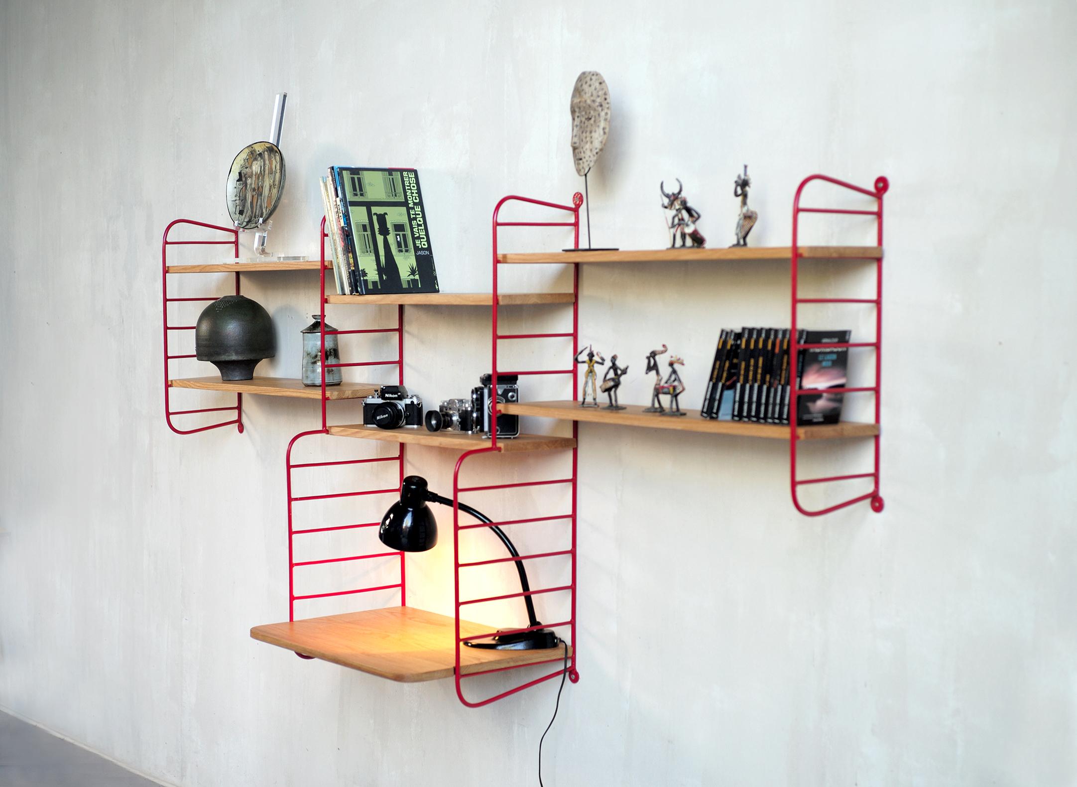 Robert Charroy, rare wall bookcase in red lacquered metal and oak edited by Mobilor, France 1950. The solid metal ladders are welded, finished with two large circular runners. The solid red oak shelves snap onto the structure, the desk top is fixed