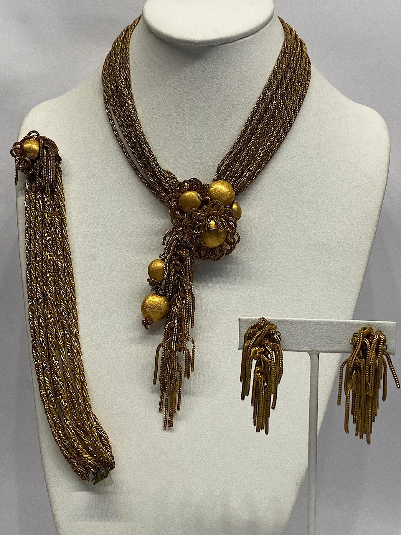 



A rare DeMario parure from the late 1940s to 1950s in an antique semi shiny and matt gold finish. The necklace and bracelet both have a dozen strands. The necklace has a central focal point of satin gold bead centered flowers with loop petals