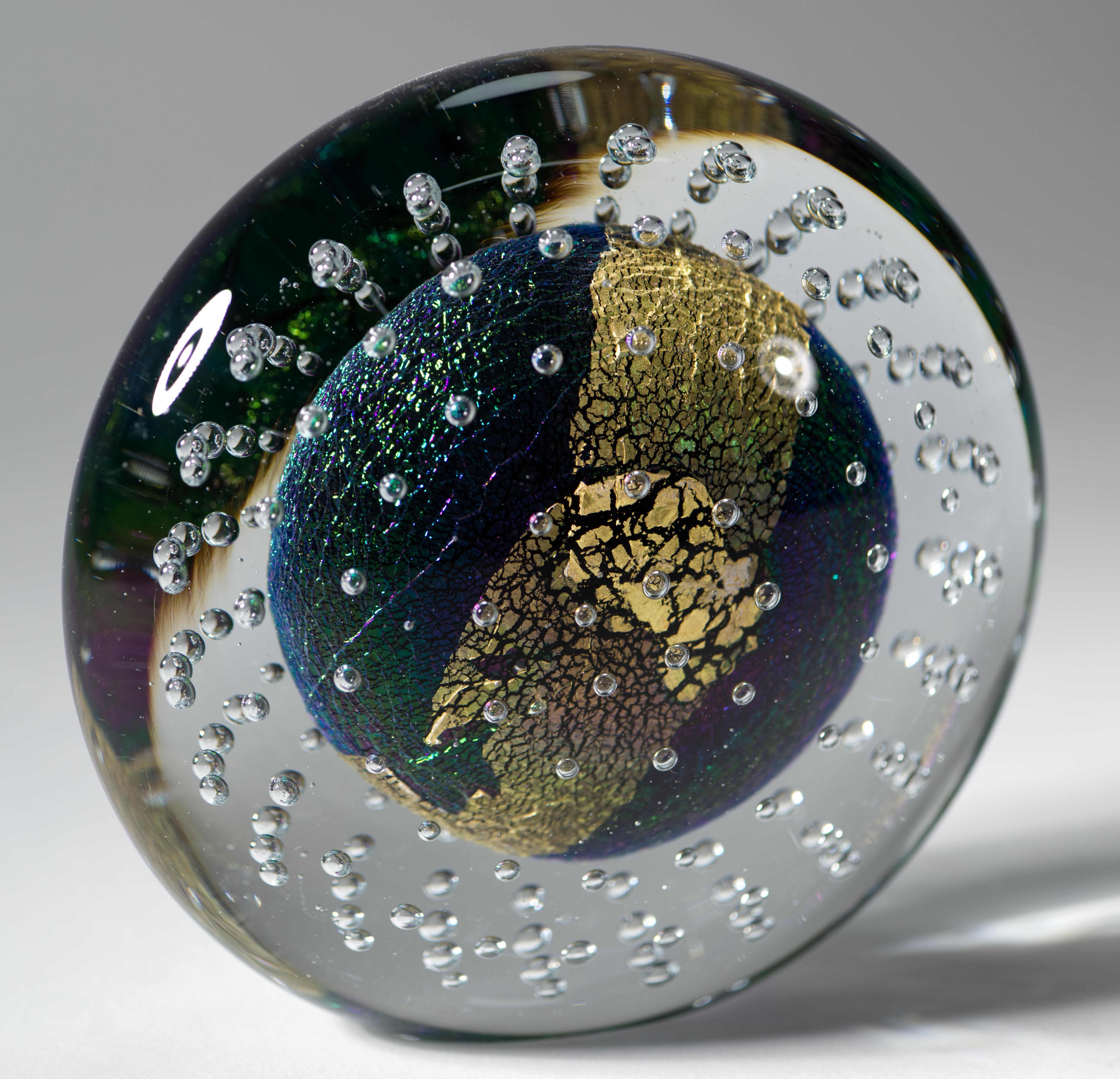  La scultura in vetro artistico vintage presenta una complessa struttura centrale di vetro colorato e dicroico fuso con frammenti di lamina d'oro stratificati, circondati da bolle controllate, racchiusi in uno strato di vetro trasparente con tecnica