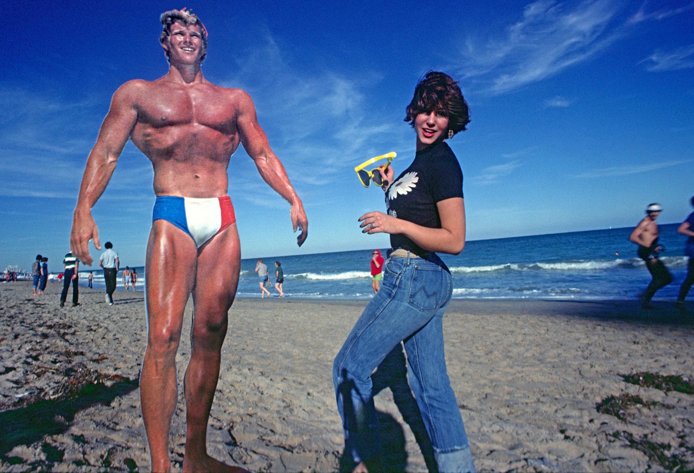 Robert Funk Figurative Photograph - Muscle Man and Female Admirer at the Beach - Staged Photography 