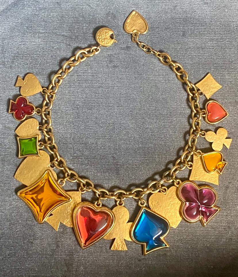 This Yves Saint Laurent necklace from the 1980s, designed by the renowned French jeweler Robert Goossens, features a playful playing card suite theme. The necklace has 17 charms representing clubs, spades, diamonds, and hearts along the front of the