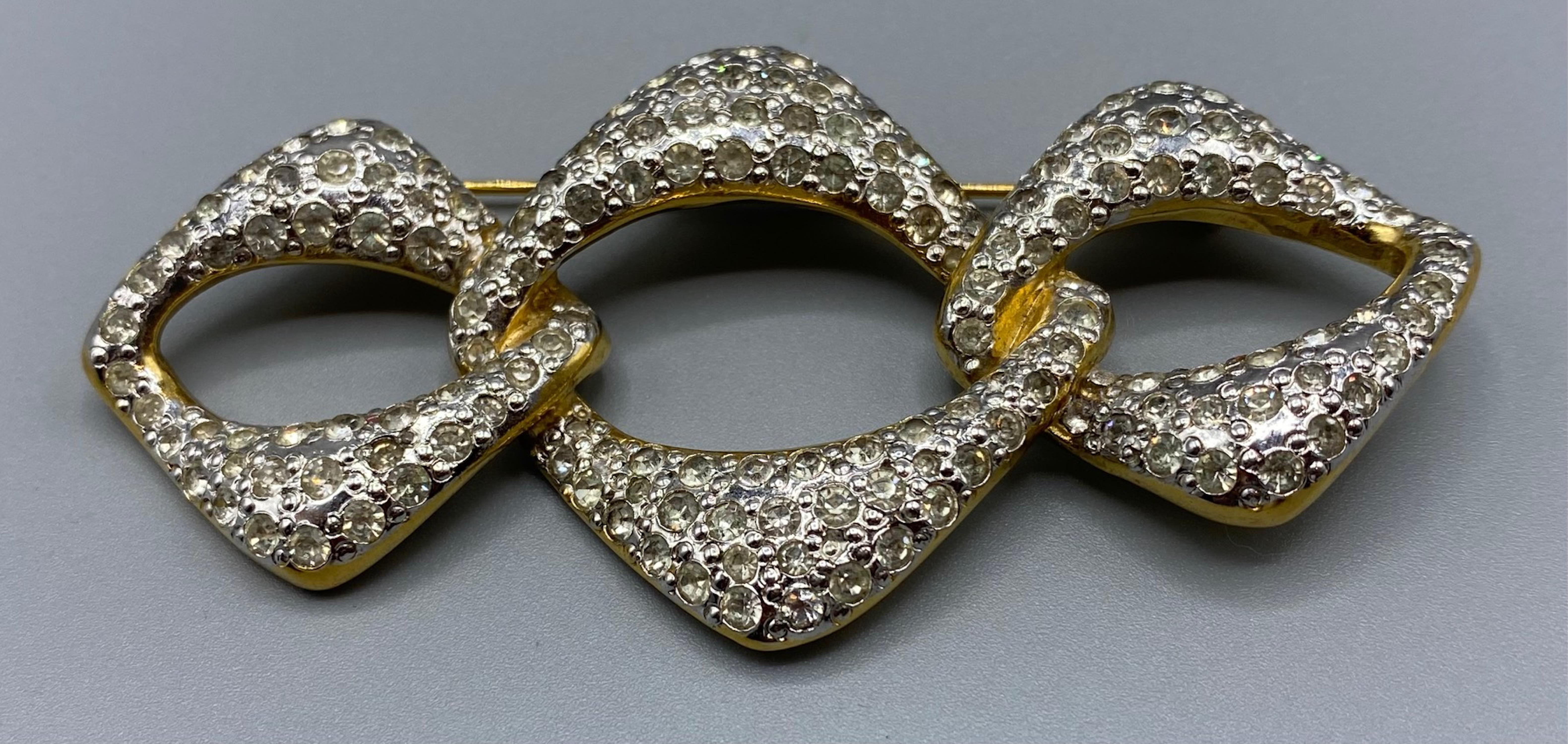 Presented is a classic link design brooch designed by Robert Goosens for Yves Saint Laurent of Paris. It is gold and rhodium plated with hand set pave' rhinestones. The brooch measures 3.5 inches wide and 2 inches tall. On the back is a rectangular