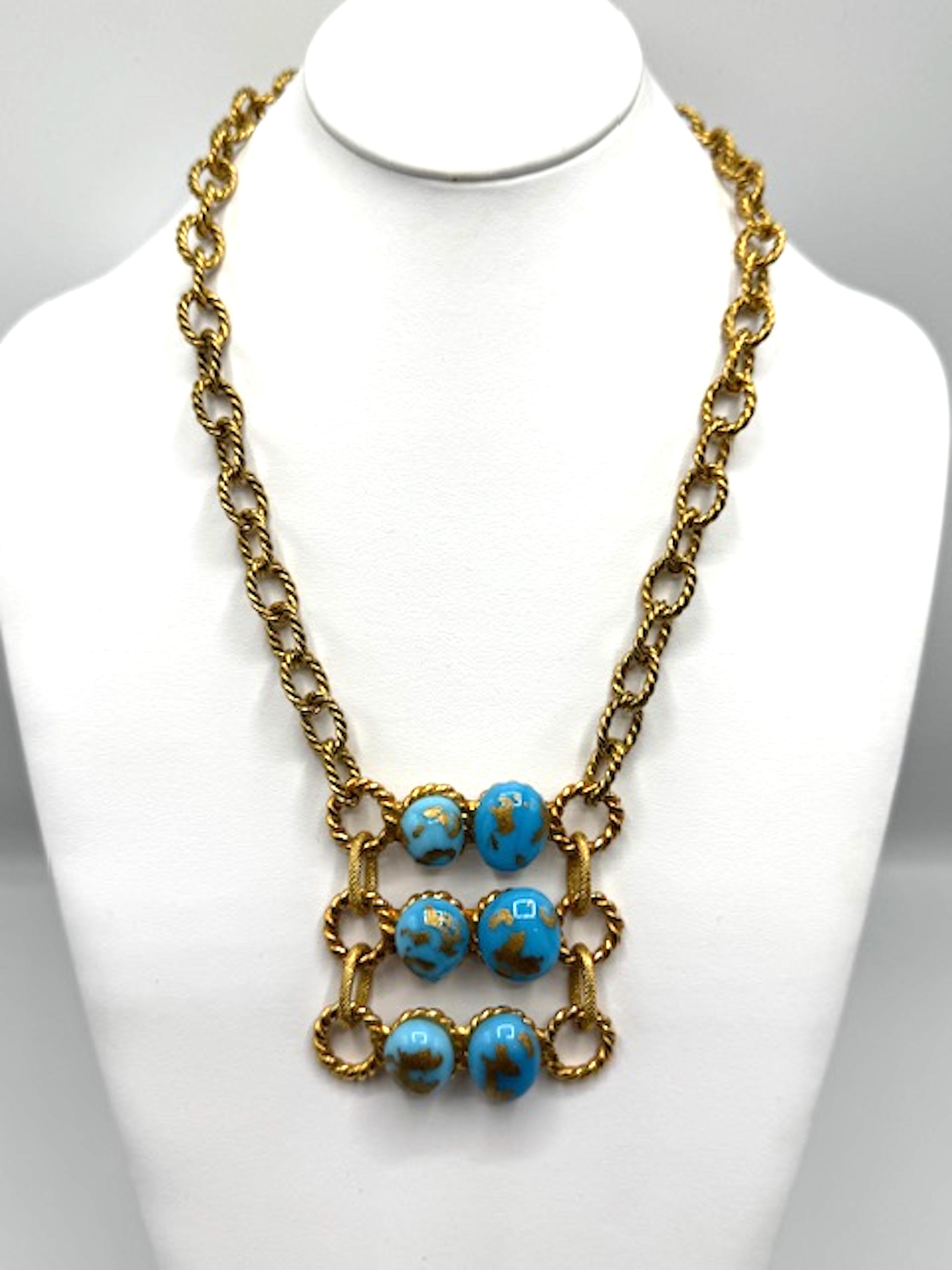 Dies ist eine auffällige Vintage-Halskette von Yves Saint Laurent, entworfen von Robert Goossens. Es besteht aus einer kühnen goldfarbenen Kette mit verschlungenen Gliedern und einem auffälligen Mittelstück aus sechs türkisfarbenen Glassteinen mit
