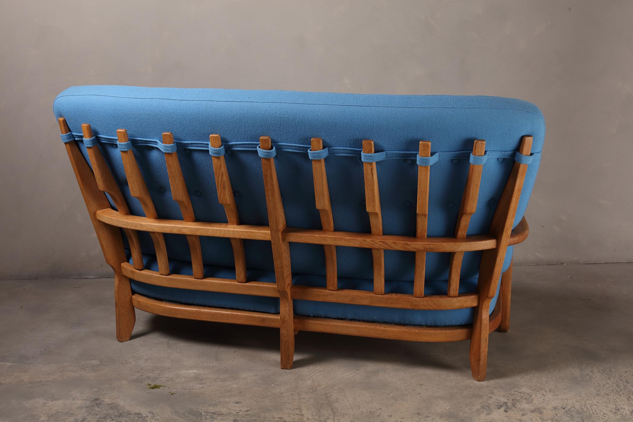 Sculptural carved oak settee is designed by Guillerme and Chambron. The design duo is known for their sculptural, crafted solid oak furniture. This comfortable sofa has an interesting open construction, featuring curved and diagonal lines. The