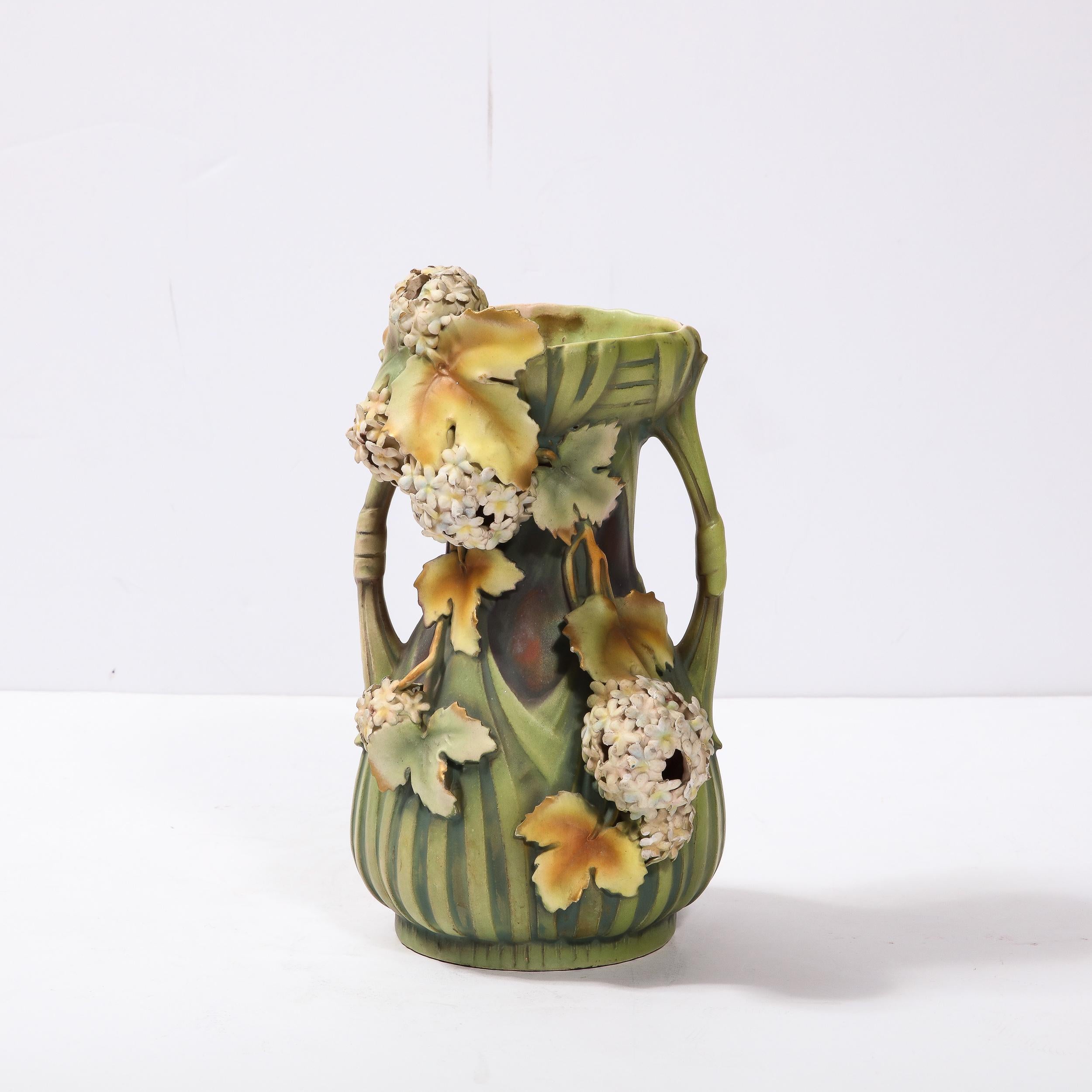 This exceptional ceramic Art Nouveau vase was created by the esteemed Austrian potter Robert Hanke circa 1900. It features a cylindrical body with a cinched mid sectioned and sculptural cylindrical open bow form supports that extend out from the