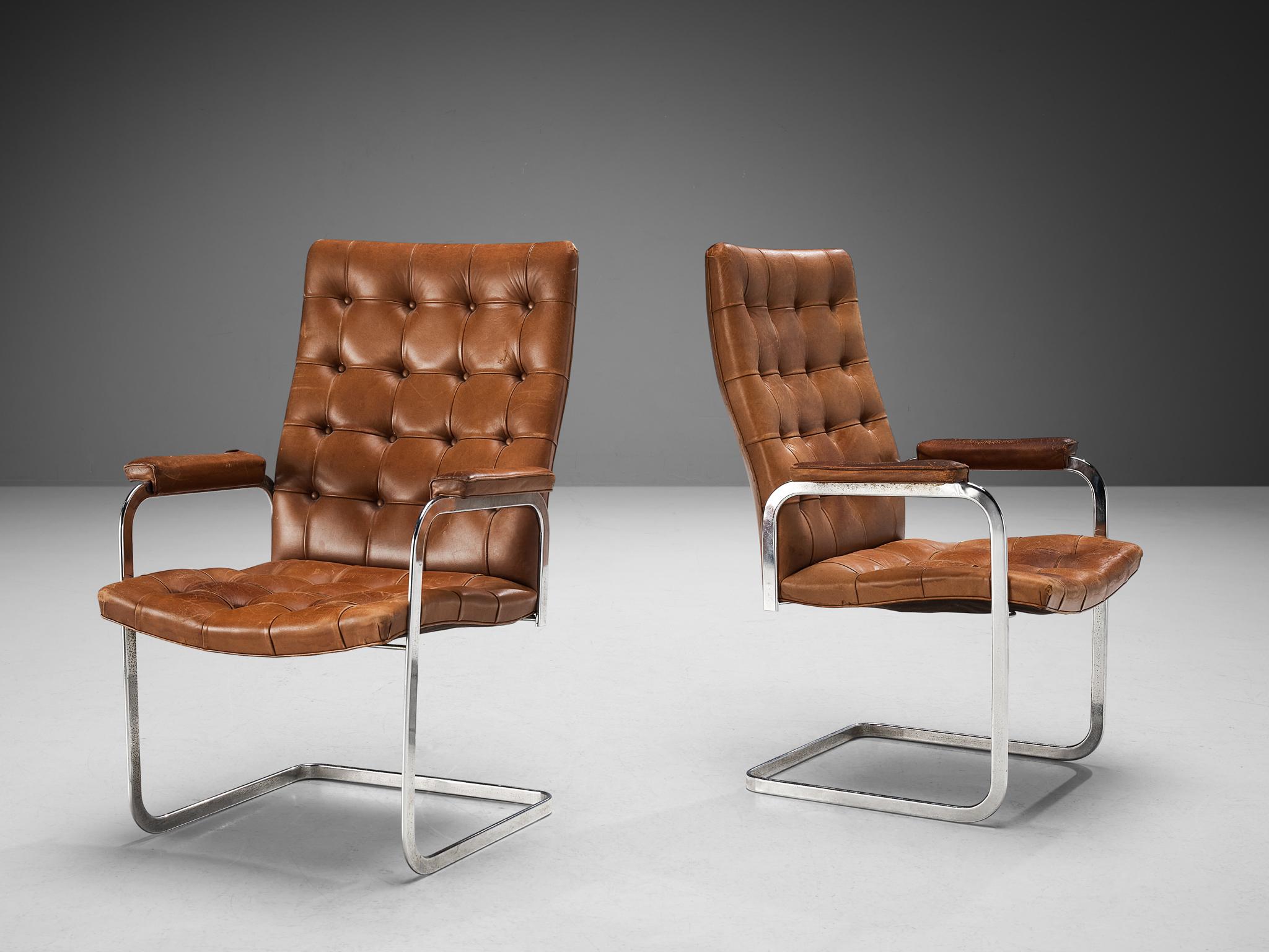 Robert Haussmann for De Sede, pair of armchairs, model 'RH-304', leather and steel, Switzerland, ca. 1950. 

This cantilevered pair of tufted chairs with leather padded armrests is designed by Robert Haussmann for De Sede. The set has a business