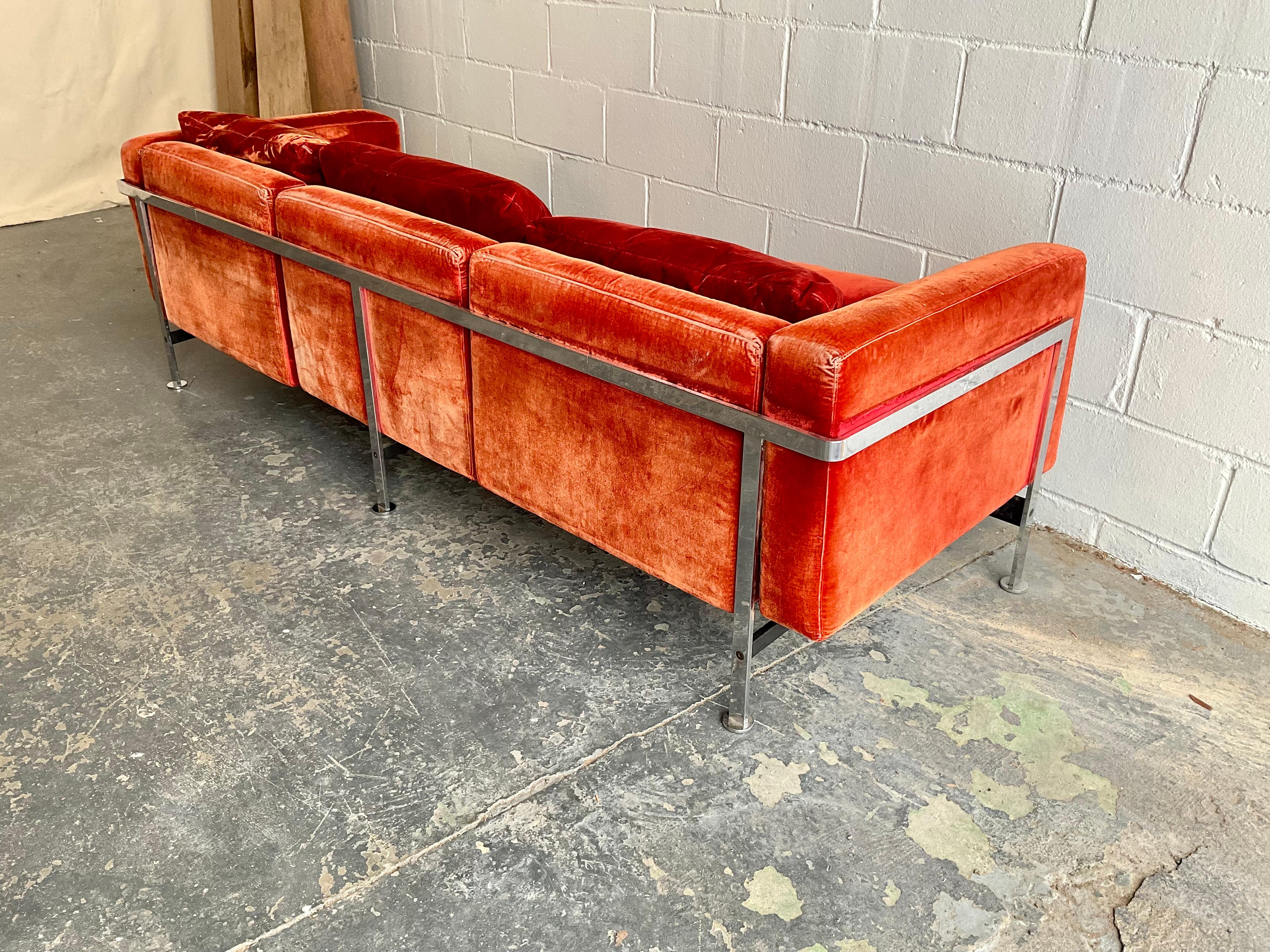 An attractive and commodious three seater sofa by Robert Haussmann for De Sede in original and distinct orange red velvet material with chrome-plated steel frame. Great lines on this confident, understated design by a company known for unrelenting