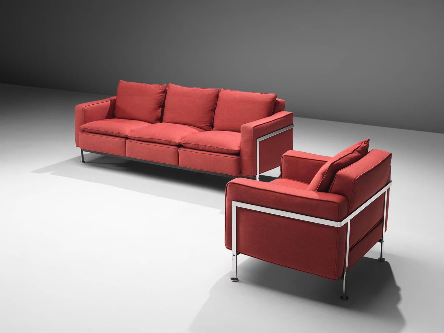 Robert Hausmann for De Sede, sofa and armchair in red fabric, steel, Switzerland, 1954.

This comfortable sofa and matching chair are designed with a chromed iron frame that functions as a basket for the cushions on the inside. The thick back and