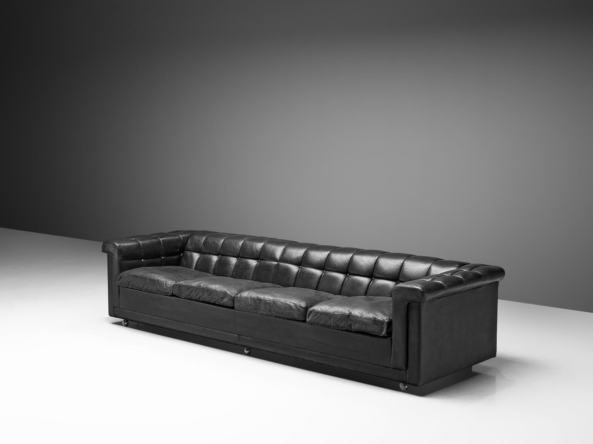 Robert Haussmann, four-seat sofa, in leather and metal, Switerland, 1970s.

This sofa in black leather has an interesting appearance of a Classic Chesterfield sofa with a modern aesthetic. The outside is tight and sleek. The black leather