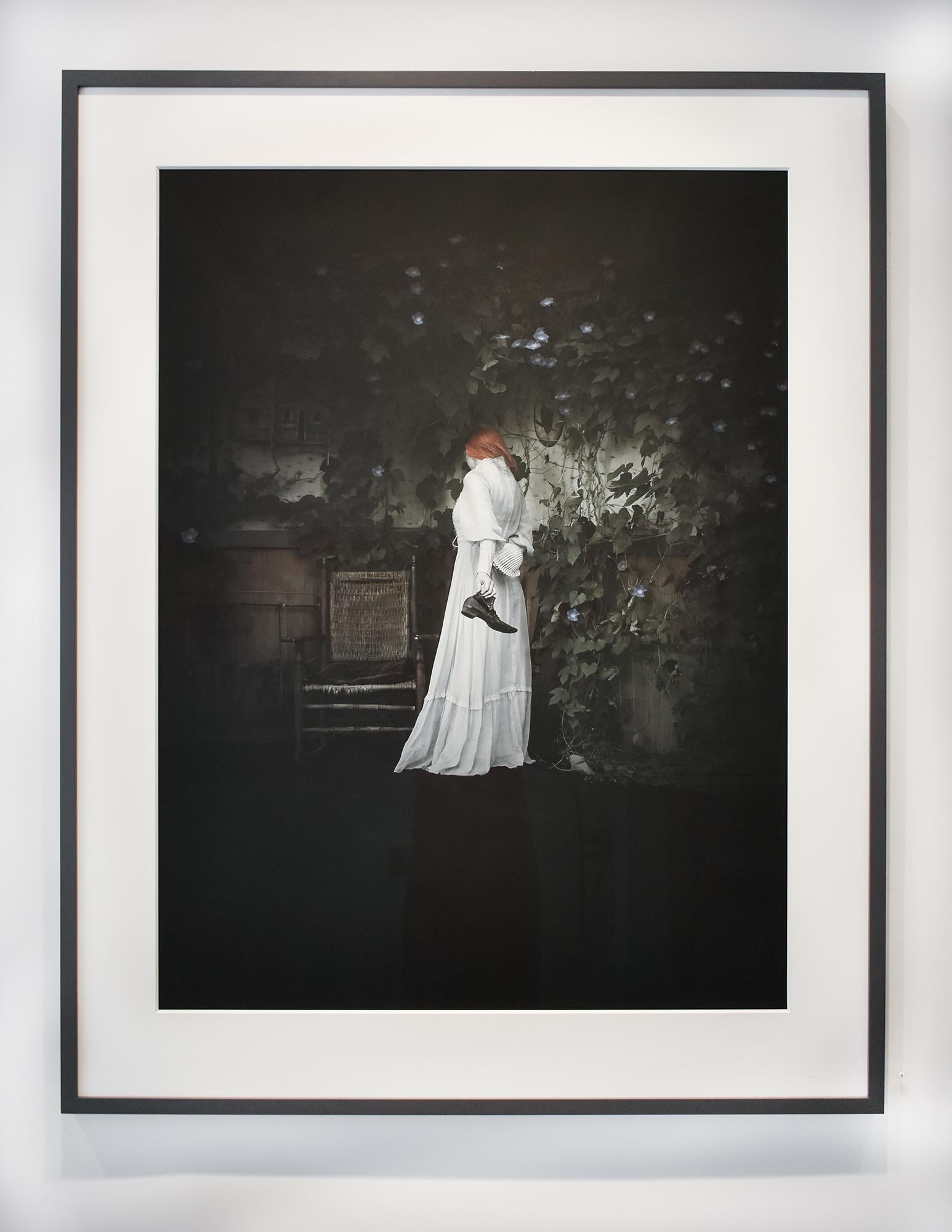 Figurative photograph of a young woman in an eerie old-fashioned interior with vines and purple morning glories 
archival pigment print, edition of 10 
40 x 30 inches, 49 x 39 inches in dark grey painted wood frame with 8-ply mat and non-glare