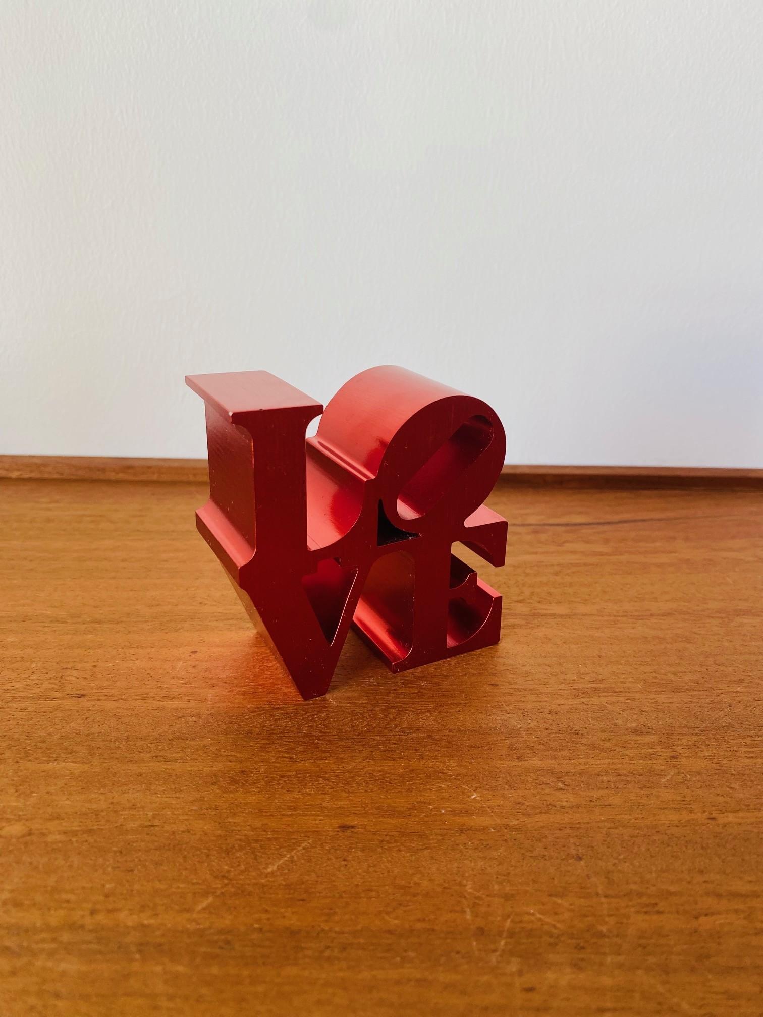 Cette interprétation très rare et cette petite édition unique de la sculpture presse-papier d'amour vintage de Robert Indiana est captivante.  Cette version en aluminium brossé rouge, très rare, attire l'attention où qu'elle soit placée.  Un ajout