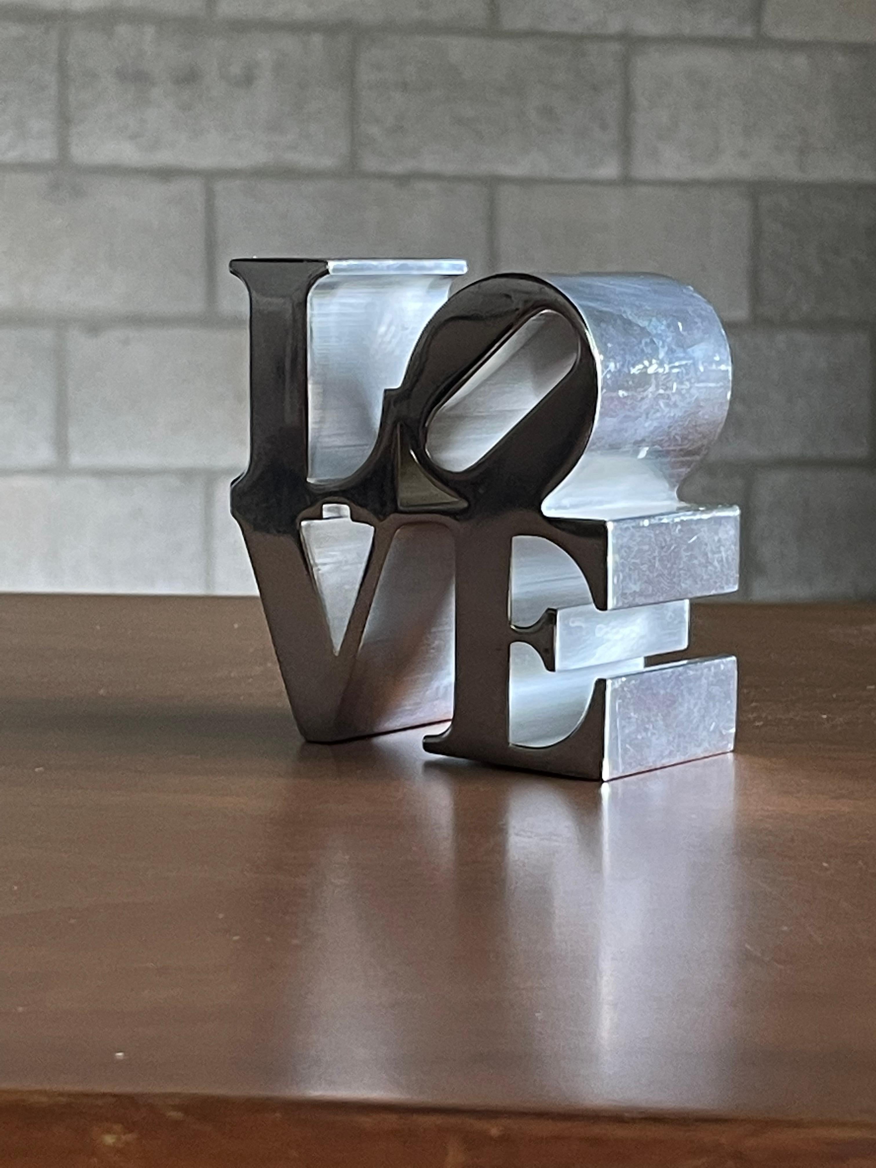 A paperweight in polished metal after Robert Indiana. Likely purchased at MoMA. This piece would add great modernist character to any desk or office environment.
