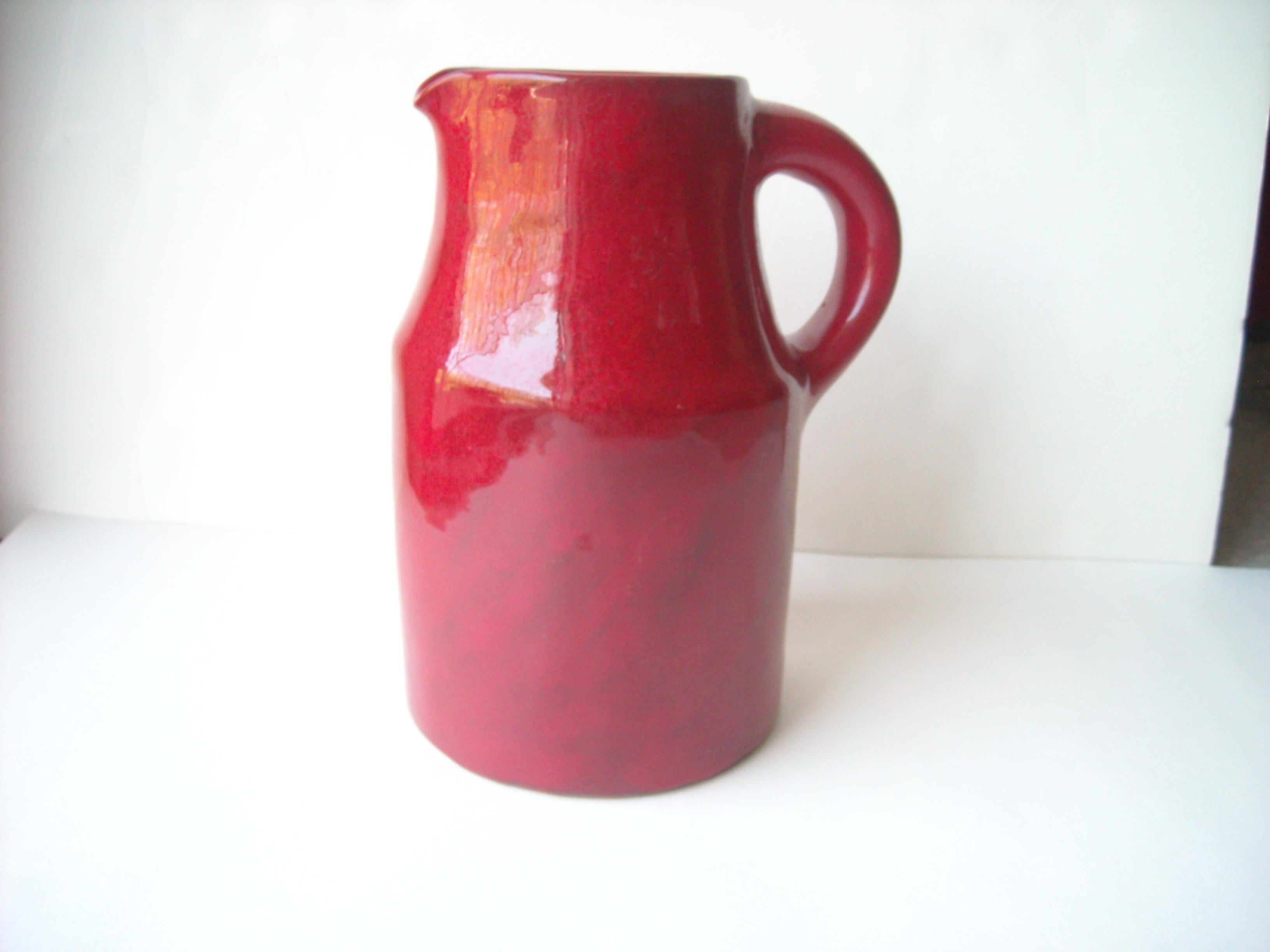 Very rare and nice pitcher for the Freres Cloutier, in a well known glaze high glossy red ceramic .the length in clouding handle is 7 1/4. Signed Cloutier R J, France.