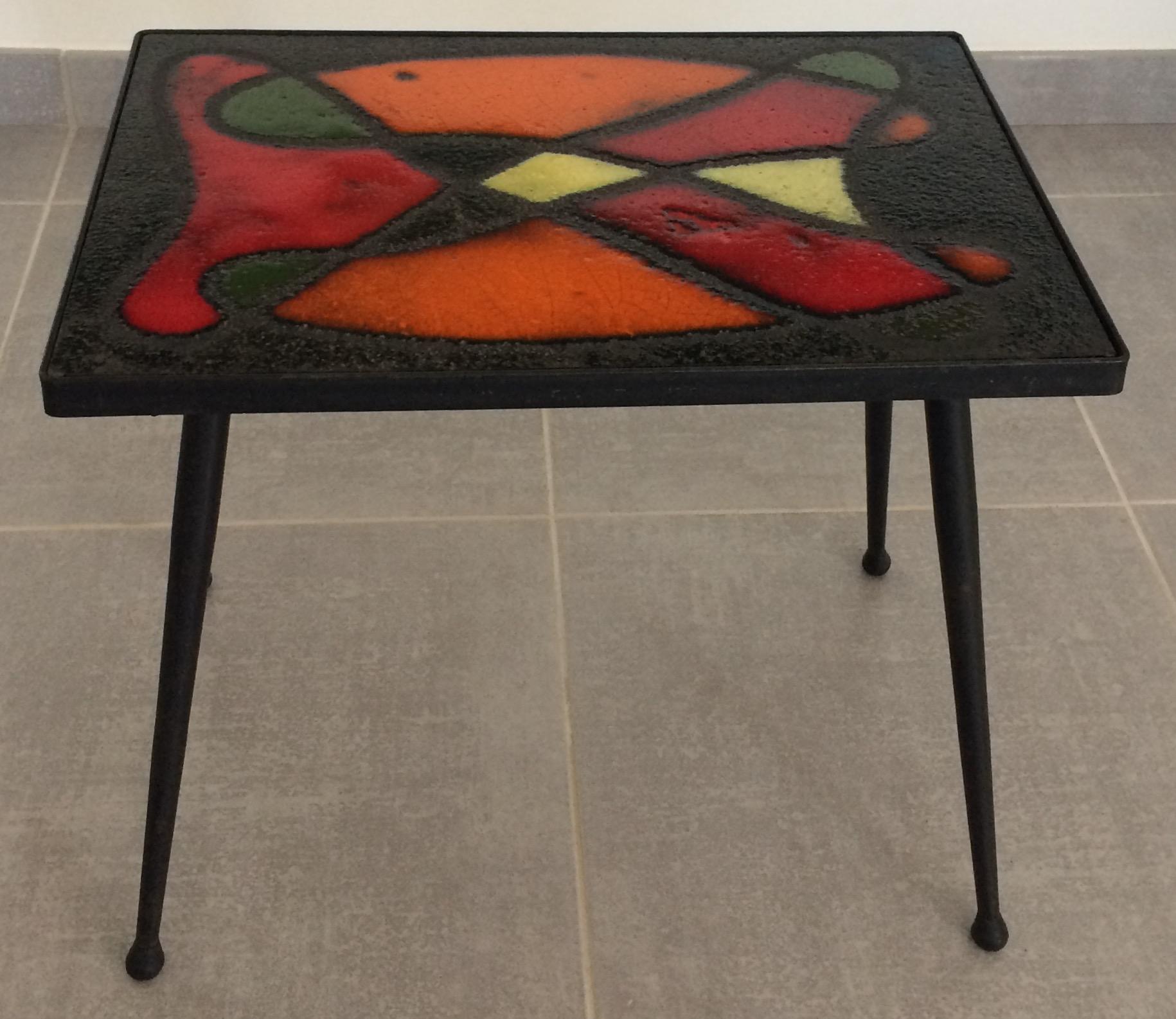 A boldly colorful glazed ceramic tile table by Jean and Robert Cloutier, circa 1960, France. 
Stunning colors of hot orange, bright red, black, grassy green and pale yellow.

This table by the dynamic design duo can be converted into artwork to be