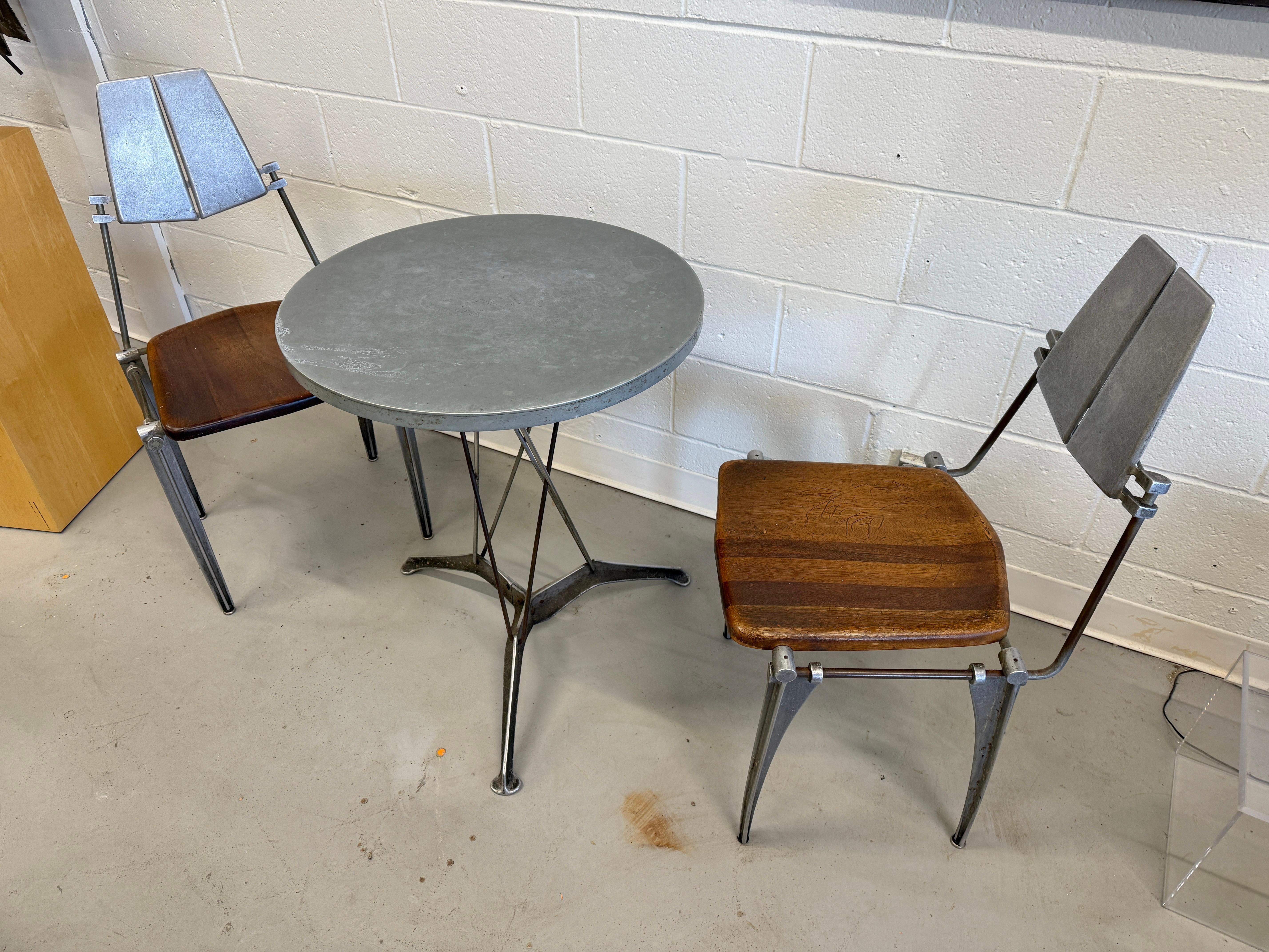 Un joli petit ensemble de salle à manger vintage en fonte d'aluminium de Robert Jostens datant des années 1970. Sièges en bois foncé. Cette table est assez rare dans cette forme et cette taille. 
Les sièges en bois sont en bon état avec quelques