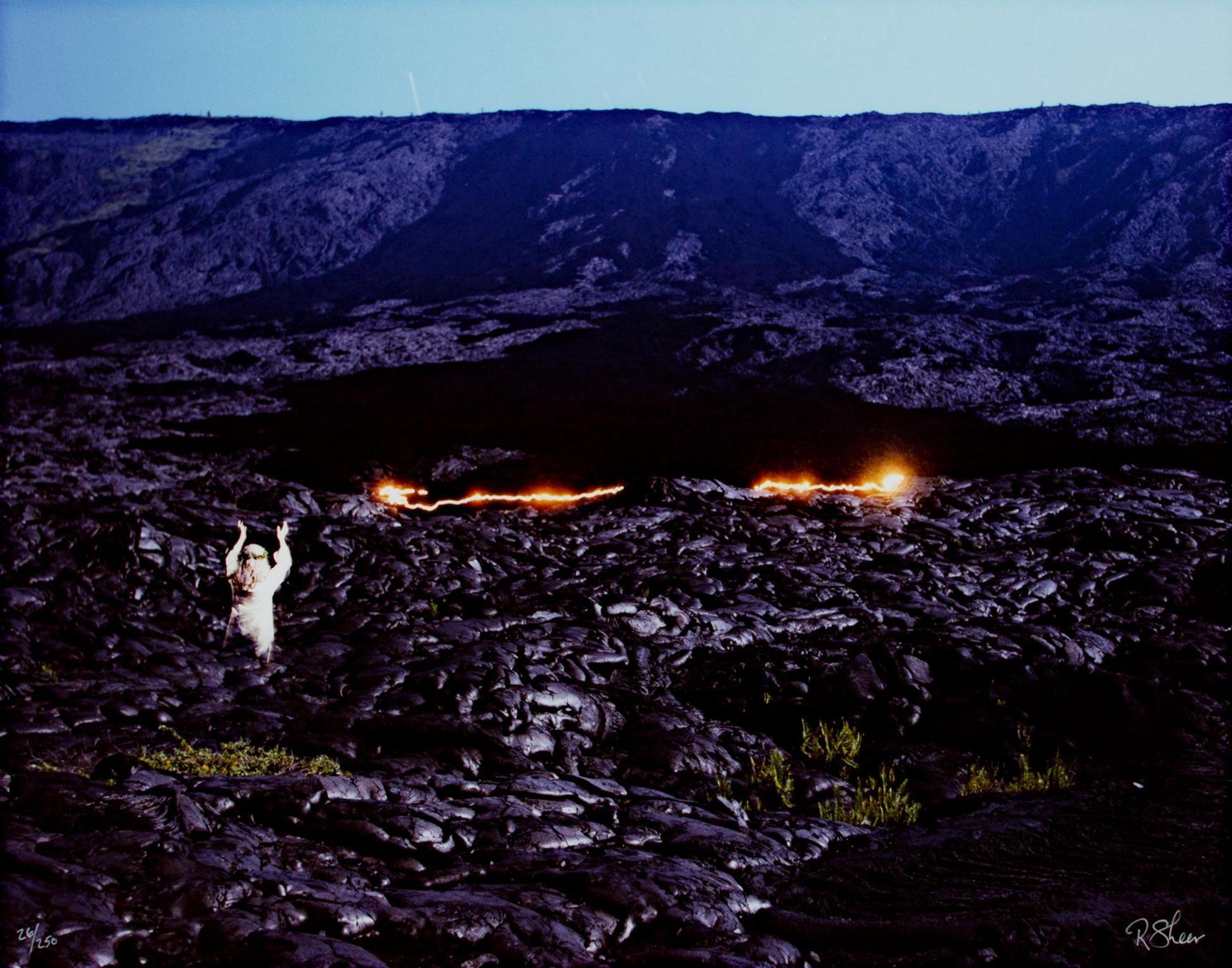 "Pele Reigniting an Old Lava Flow" is an original fine-art performance photograph by Robert Kawika Sheer. The artist signed this piece in the lower right and editioned in the lower left.  Edition 26/250. This piece depicts a hardened lava field, a
