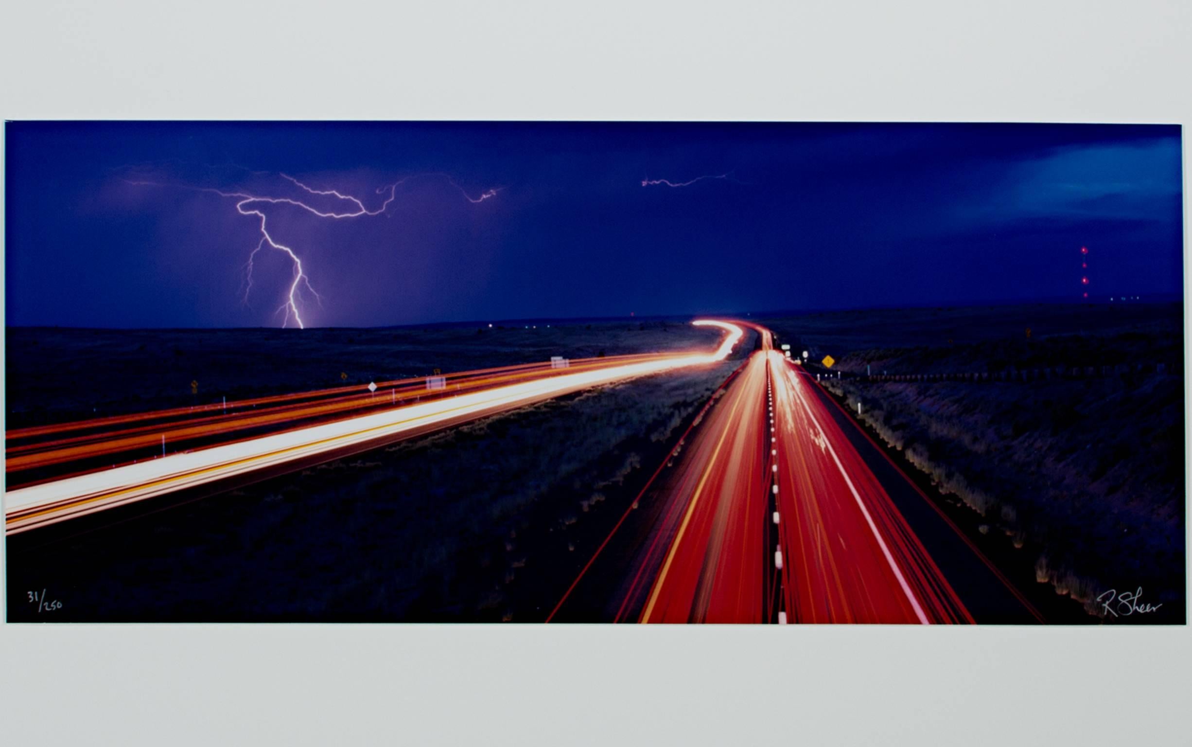 "Lightning Along Route 66 Arizona - Navajo Exit" is a long-exposure photograph by Robert Kawika Sheer. This limited edition photograph depicts the light trails from cars along America's famous Route 66. Kawika-Sheer also manages to catch a brilliant