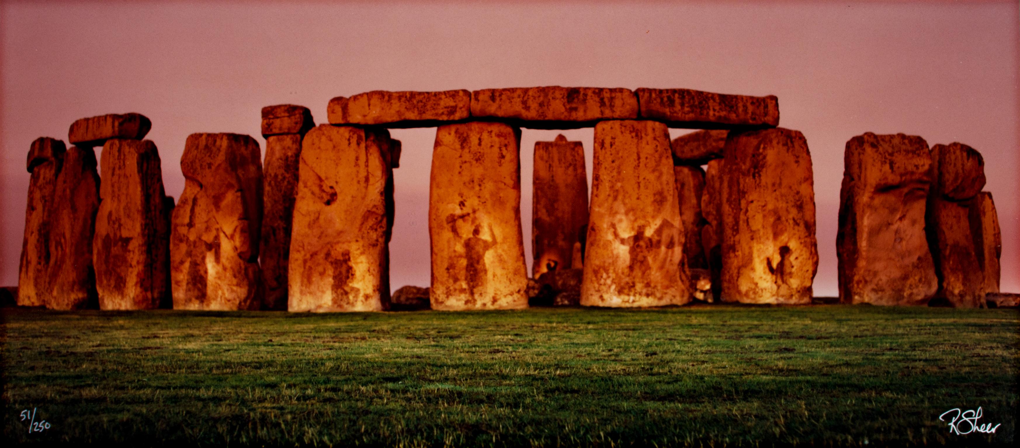 "The Spirits of Stonehenge" is an original fine-art photograph by Robert Kawika Sheer. The image is signed in the lower right and editioned in the lower left. Edition 51/250. The image depicts Stonehenge against a pink sky. The megaliths are cast in