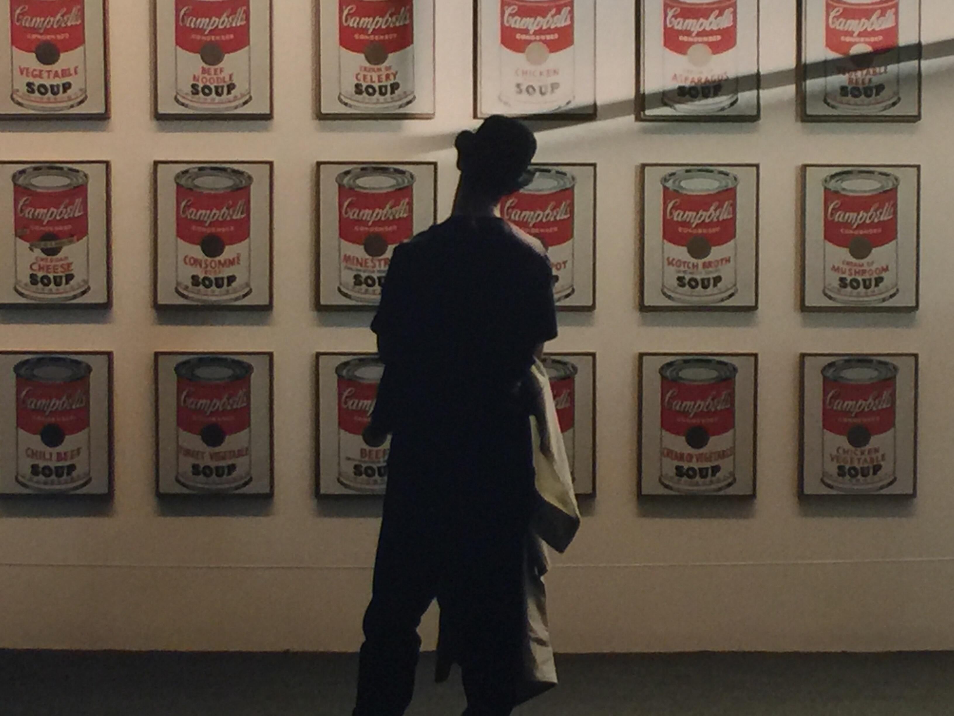 This is a singular original vintage photograph from Robert Kent Sharpe's (1930-2016) personal collection capturing a moment in time of an art observer admiring Andy Warhol's Soup Cans.  This is a series of Mr. Sharpe's human observation projects and