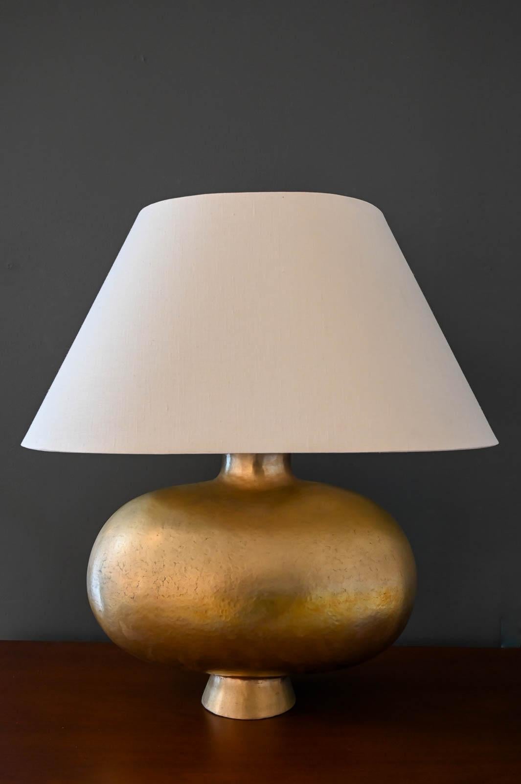Robert Kuo for McGuire 24K Hammered Gold Plated 'Cocoon' Table Lamp, ca. 2000.  Beautiful hand hammered copper body with 24K Gold Plate, Repoussé.  This rare and highly desirable lamp offers the original linen shade with dual light bulb sockets and