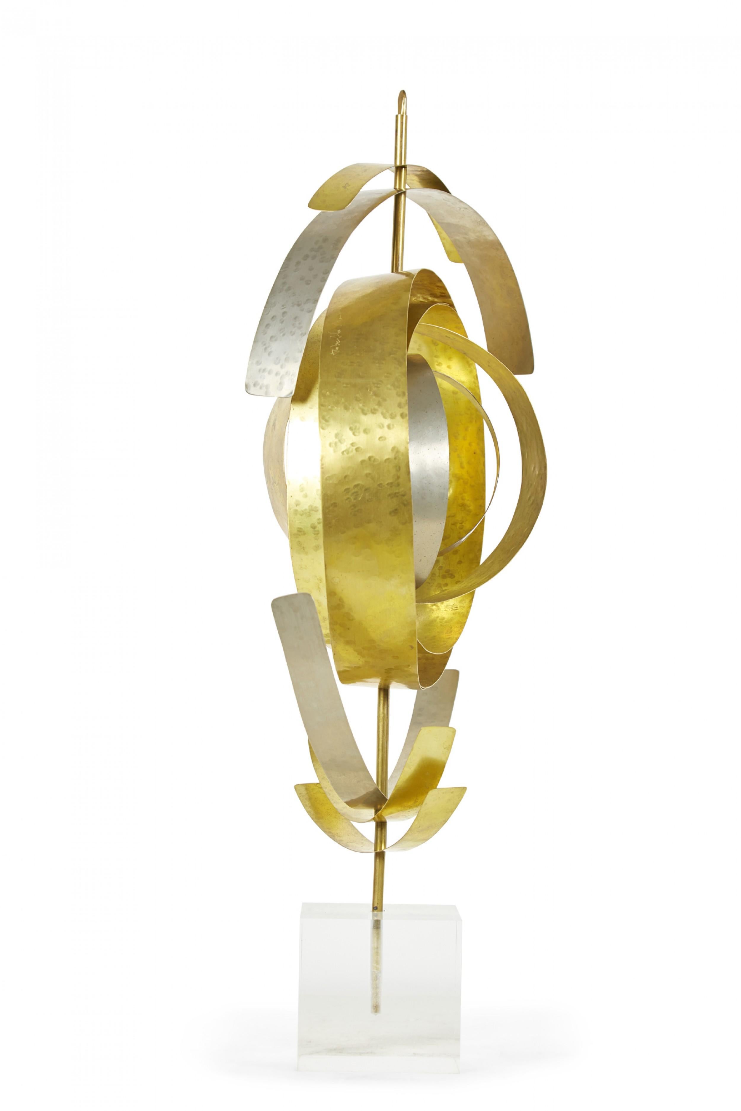 Contemporary abstract sculpture comprised of a many curved hammered nickel and brass pieces mounted on a movable spiraling pattern on a brass rod anchored in a lucite base titled, 