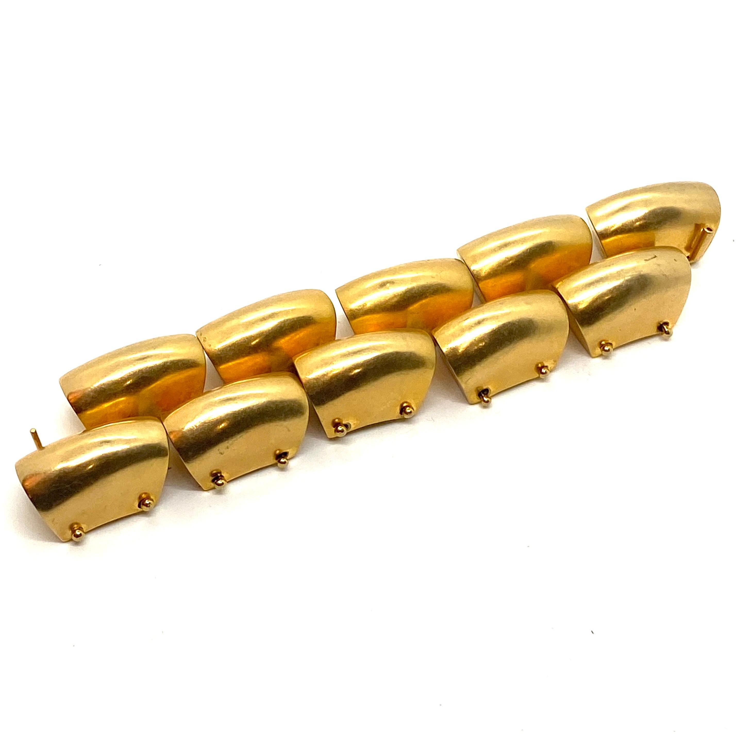 The matte gold plated brass Tire Track link bracelet by Robert Lee Morris is typical of his chunky and gutsy style of fashion jewelry. Created by multiple techniques that gave a truncated, chopped and organic casting that could be turned into a