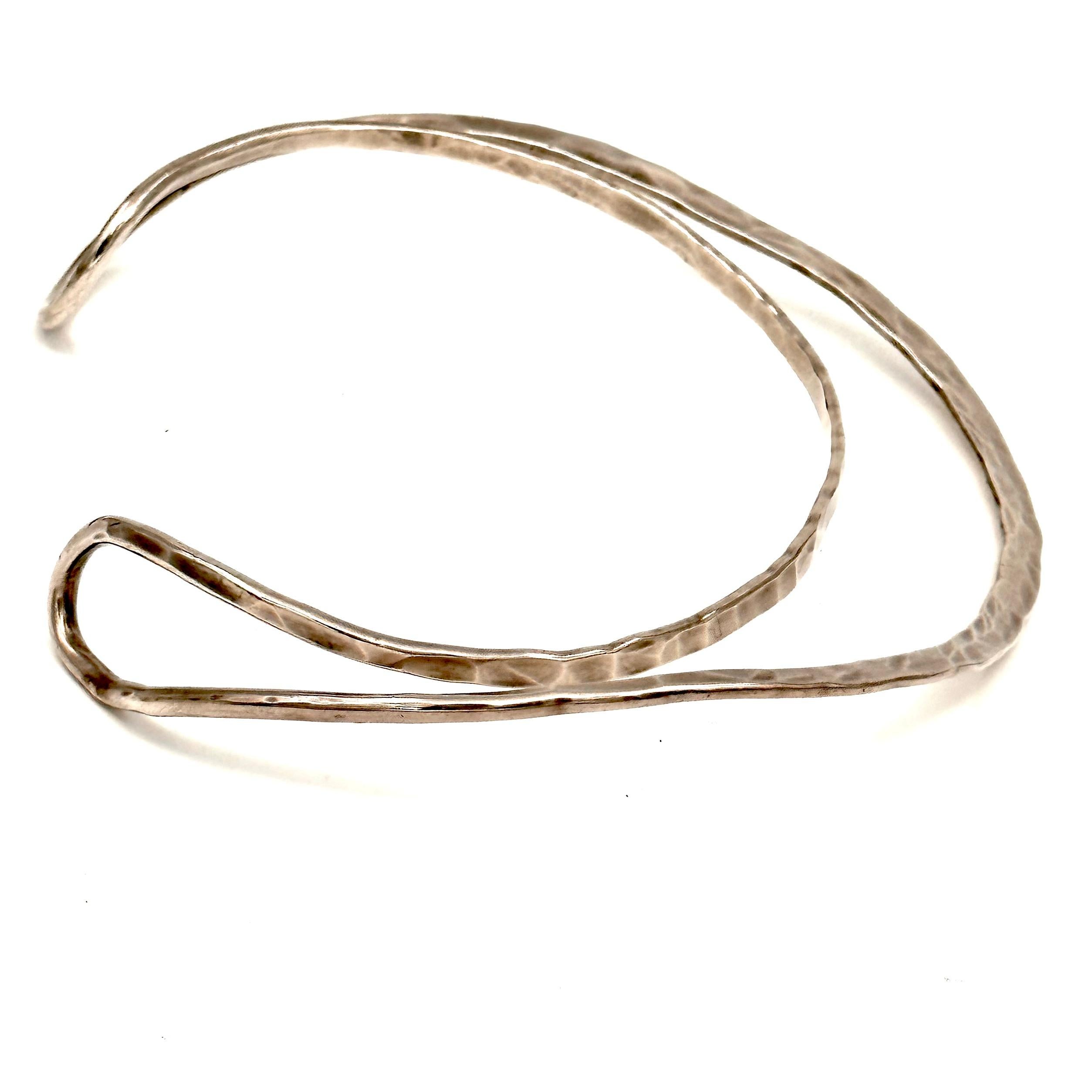 Forged in heavy sterling silver wire, this handsome and dramatic neckband fits the neck body form just perfectly, with large looping forms that are hammered so there is a thick and thin flow to the metal. Created 1991, after a class in