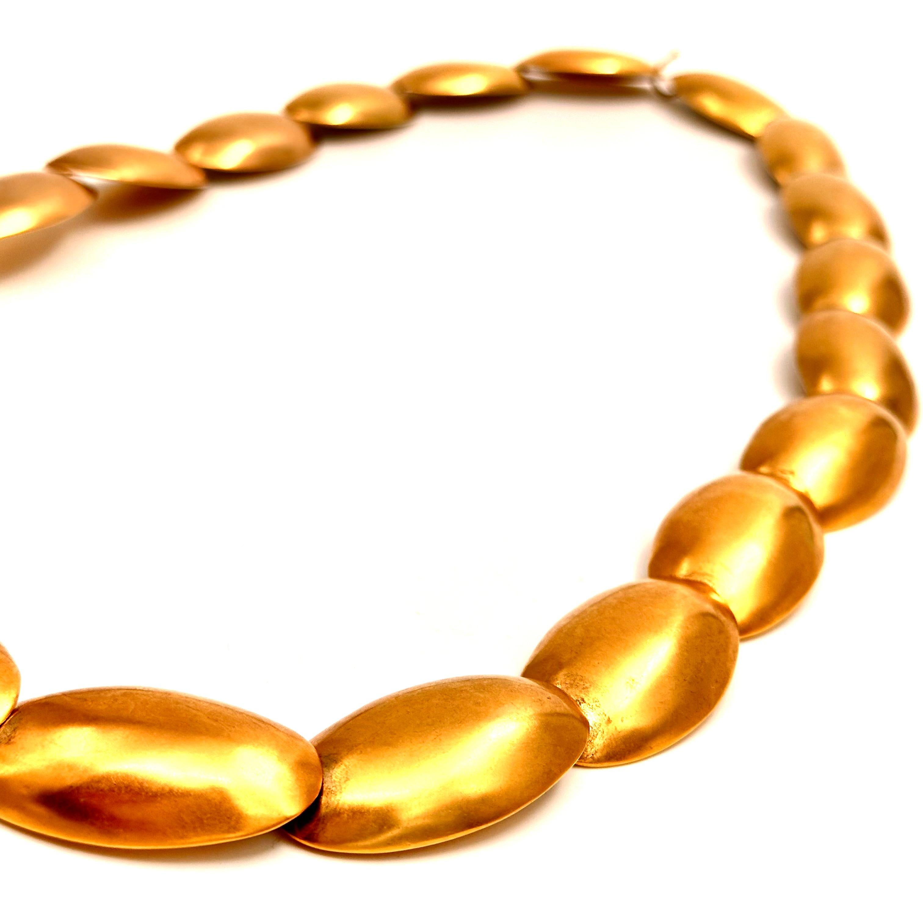 Created in 1987 for the Donna Karan collections, where the theme was soft pebbles, this belt length necklace is composed of repeating egg forms that are solid brass, plated in a semi shiny gold. Used as belts these softly gliding forms added to the