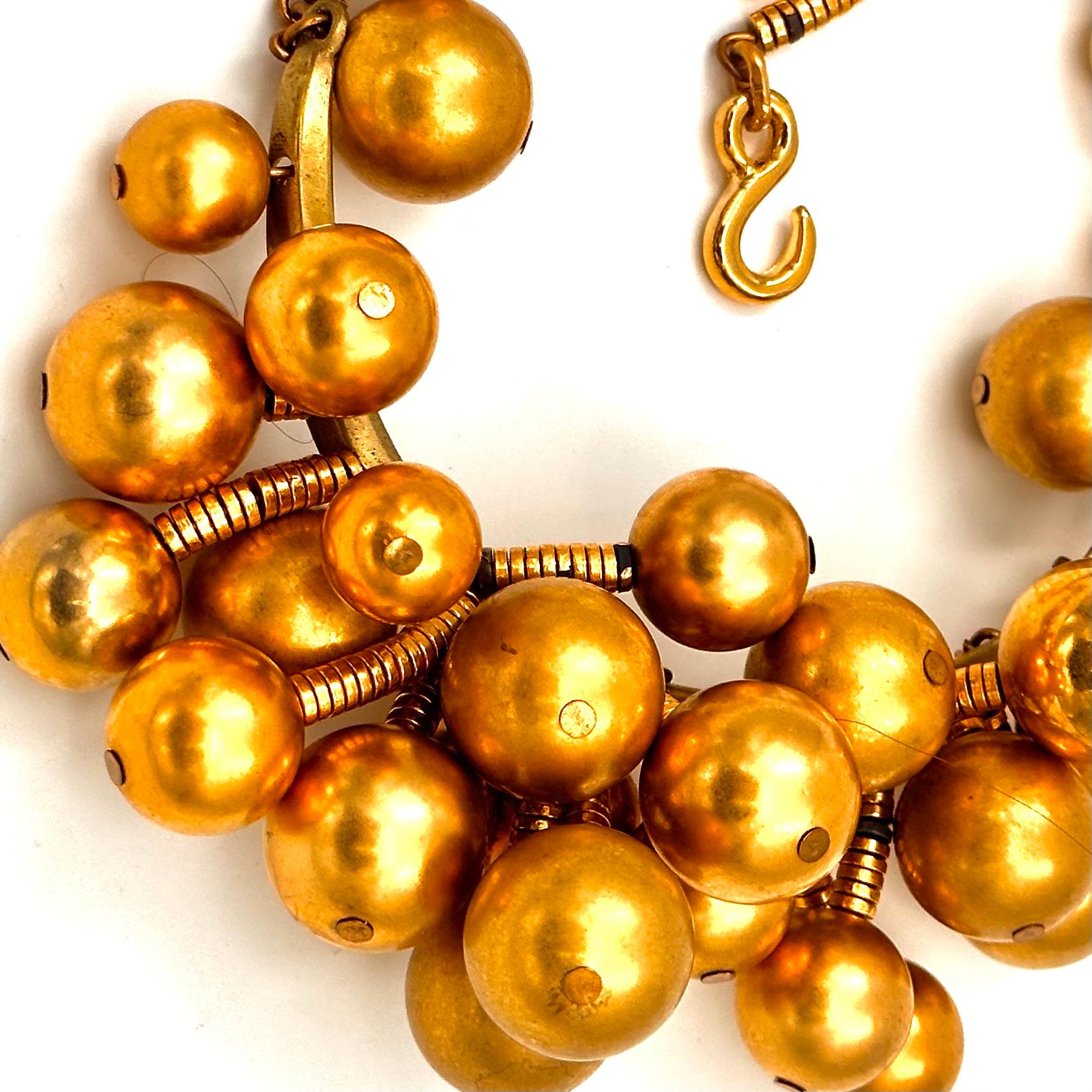What a fun necklace this one is, with the explosion of gold plated brass ball beads that are rooted to a curved brass base that sits just at the base of the neck. There is a long 13' chain that comes off the frontal horseshoe of ball clusters, that