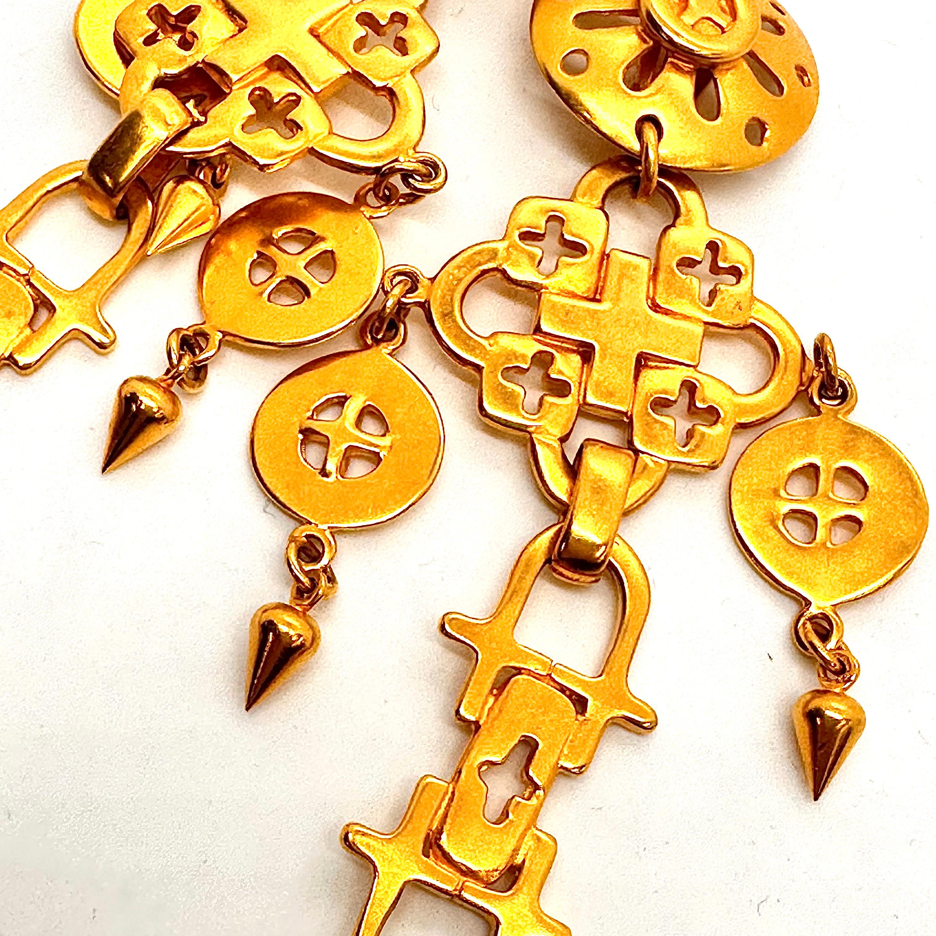 Exotic Bold Gold drop dead chandelier earrings by Robert Lee Morris are lightweight and dramatic fun. Easy to wear clips, the design is composed of many cast element using the cross theme. Created in 1992 as part of the huge trend in fashion and