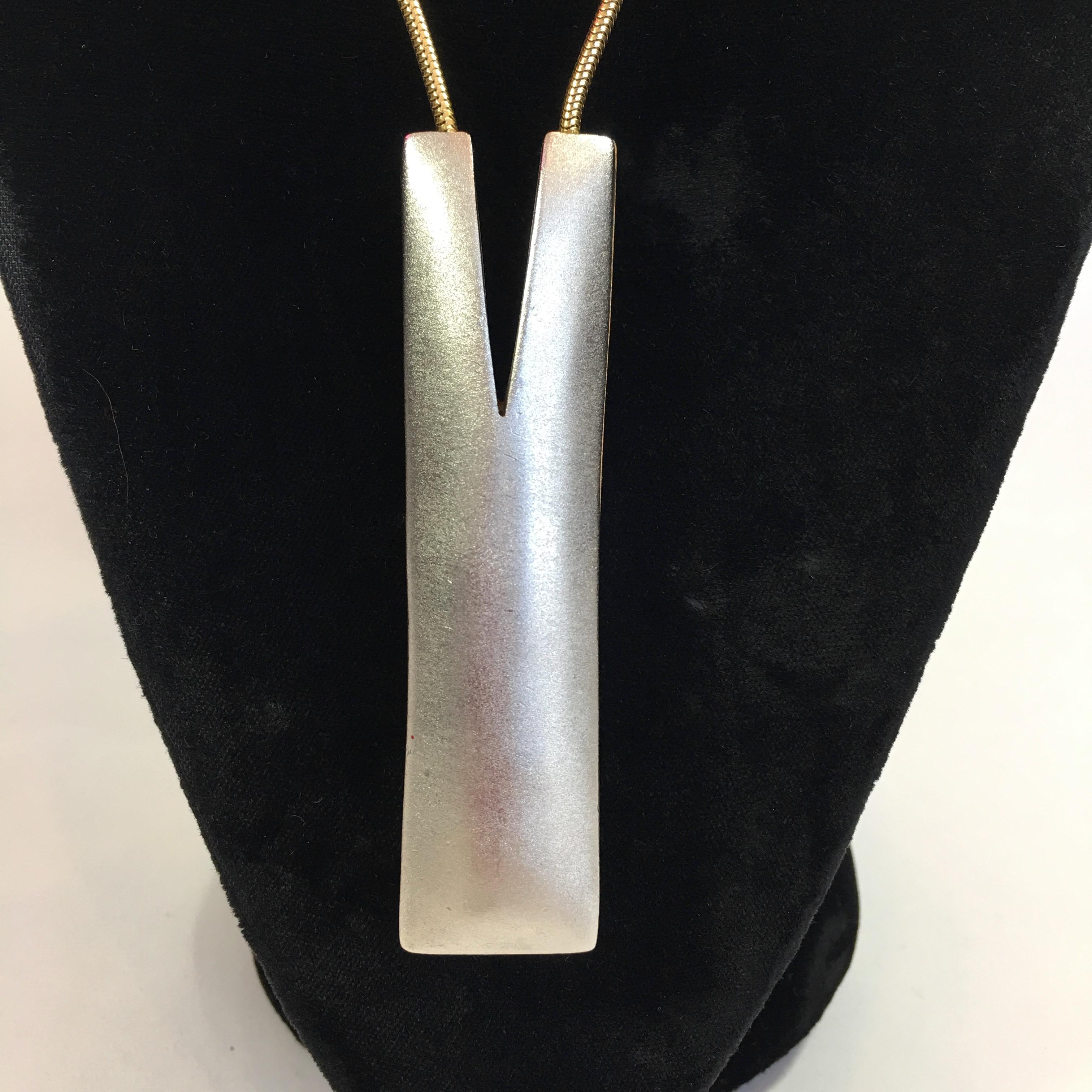 Modernist Reversible Matte Gold/Silver Necklace. 
Long round snake chain. Pendant in a modern M shape. Necklace has no logo markings on it. 
Item is in very good vintage condition.

Measurements is as follows:
Pendant drop (from back neck)-