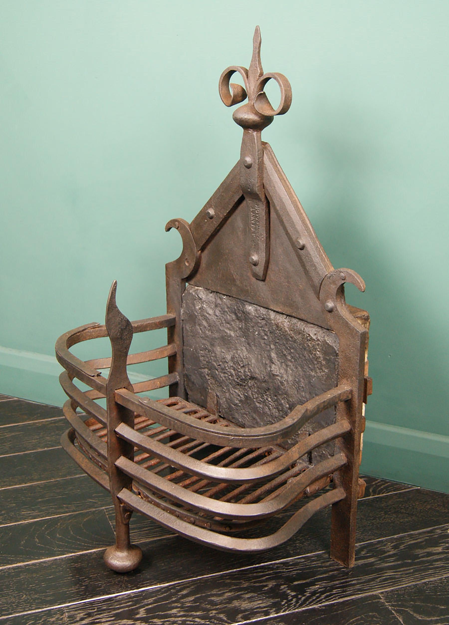 An important Scottish Arts & Crafts fire basket made and stamped by James Bennet, Robert Lorimer’s chief blacksmith. The semi-circular railed basket is supported by a central front leg, with a shaped riveted fire back flanked by crescent hooks and