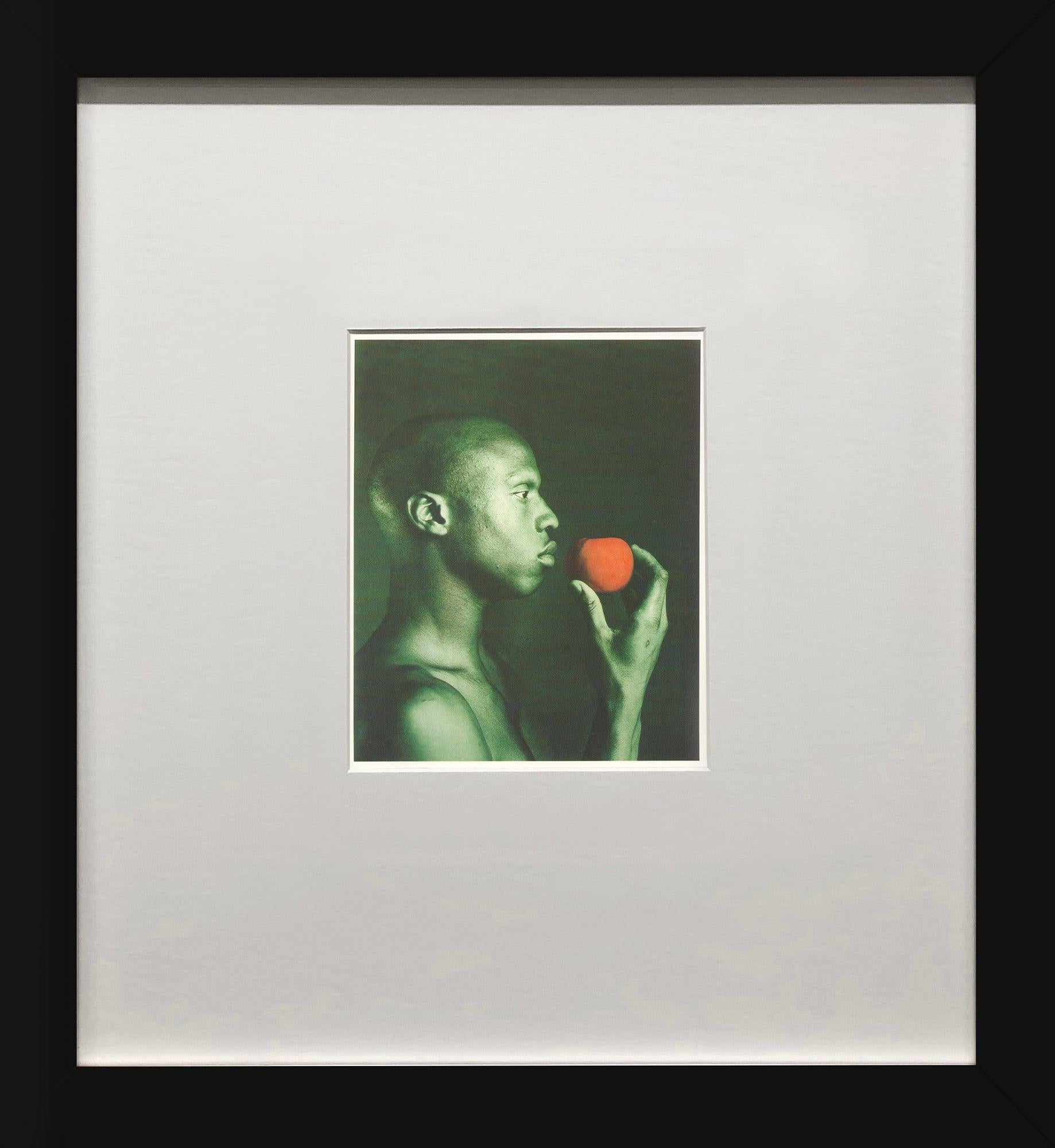 Cette image saisissante de Robert Mapplethorpe, intitulée Untitled, 1985, est tirée d'un coffret de 1991 publié par teNeues Publishing Company et imprimé en Allemagne. Dans ce portrait, le modèle tient un objet orange - peut-être un fruit - devant