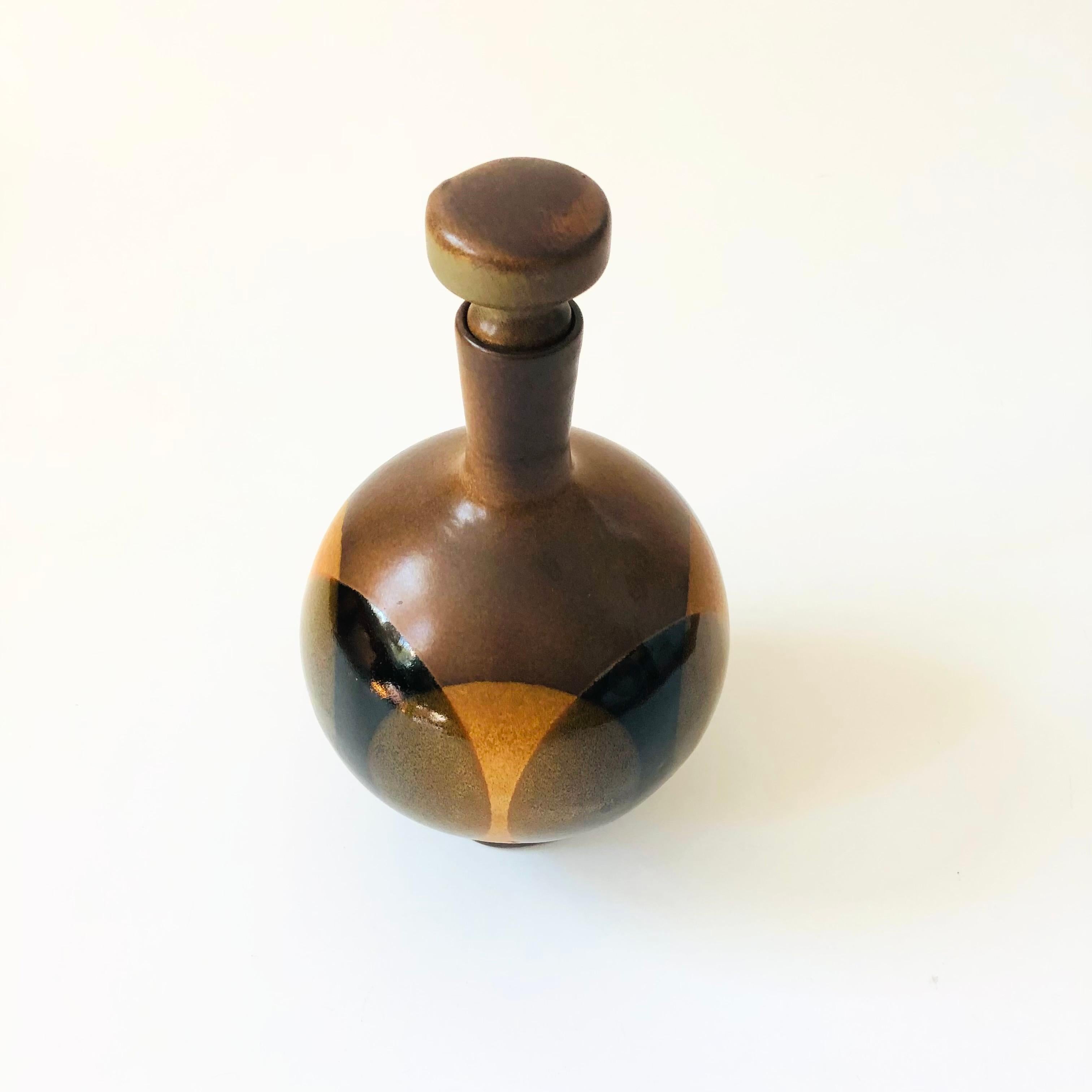 A mid century pottery decanter designed by Robert Maxwell for Pottery Craft.  Features overlapping glazes in brown and black. Marked on the base PC.

