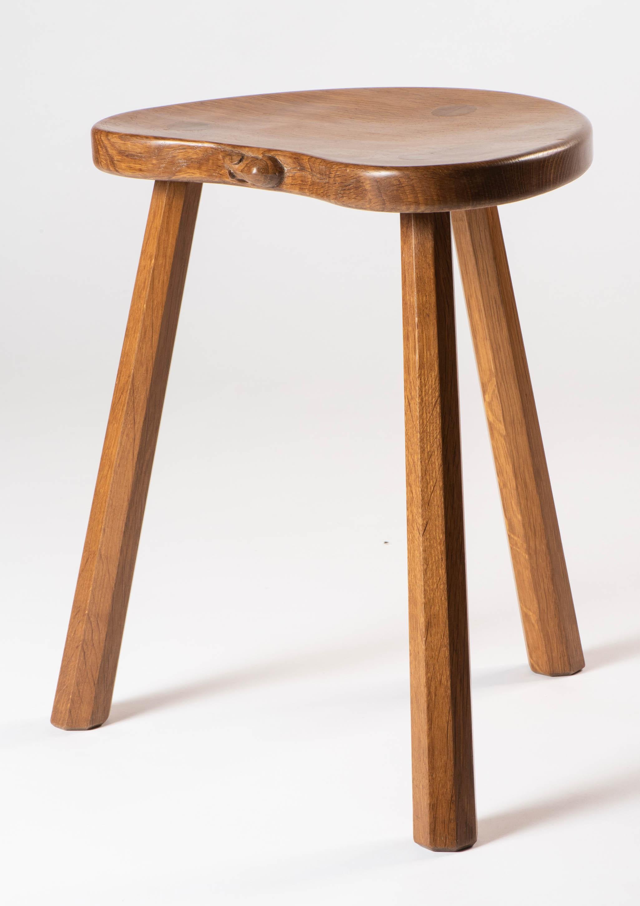 A Robert “Mouseman” Thompson Milking stool.
Adzed kidney seat supported on octagonal legs.
Large dowels to the top.
Oak
Carved mouse 
English
circa 1950.
  