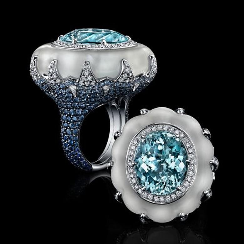 Cocktail ring, centering an oval-shaped natural Paraiba tourmaline weighing 15.03 carats, encircled by a row of round-cut diamonds and carved quartz, mounted in a fancy 18k white gold setting pavé-set with round-cut diamonds and blue sapphires,